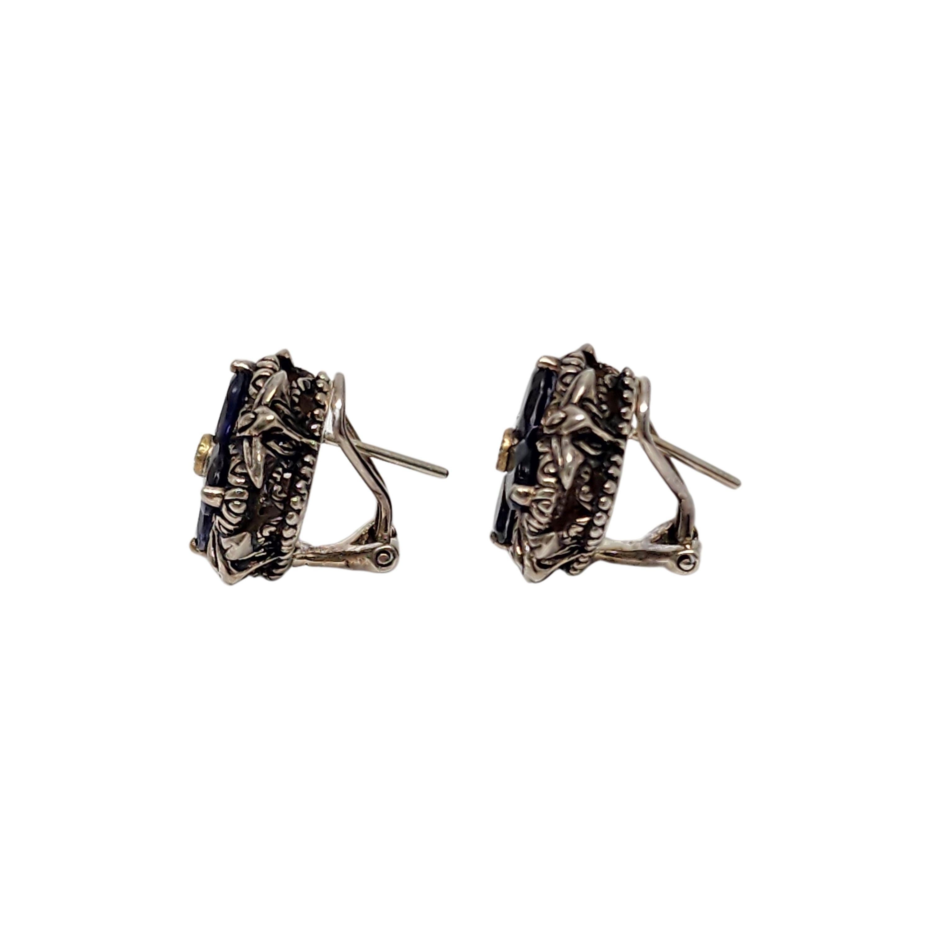 Sterling silver 18K yellow gold accent iolite flower earrings by Barbara Bixby.

A beautiful pair of flower earrings featuring oval blue/purple iolite stone petals, clear stone center bezel set in 18K yellow gold accent bezel. Omega backs.

Measures