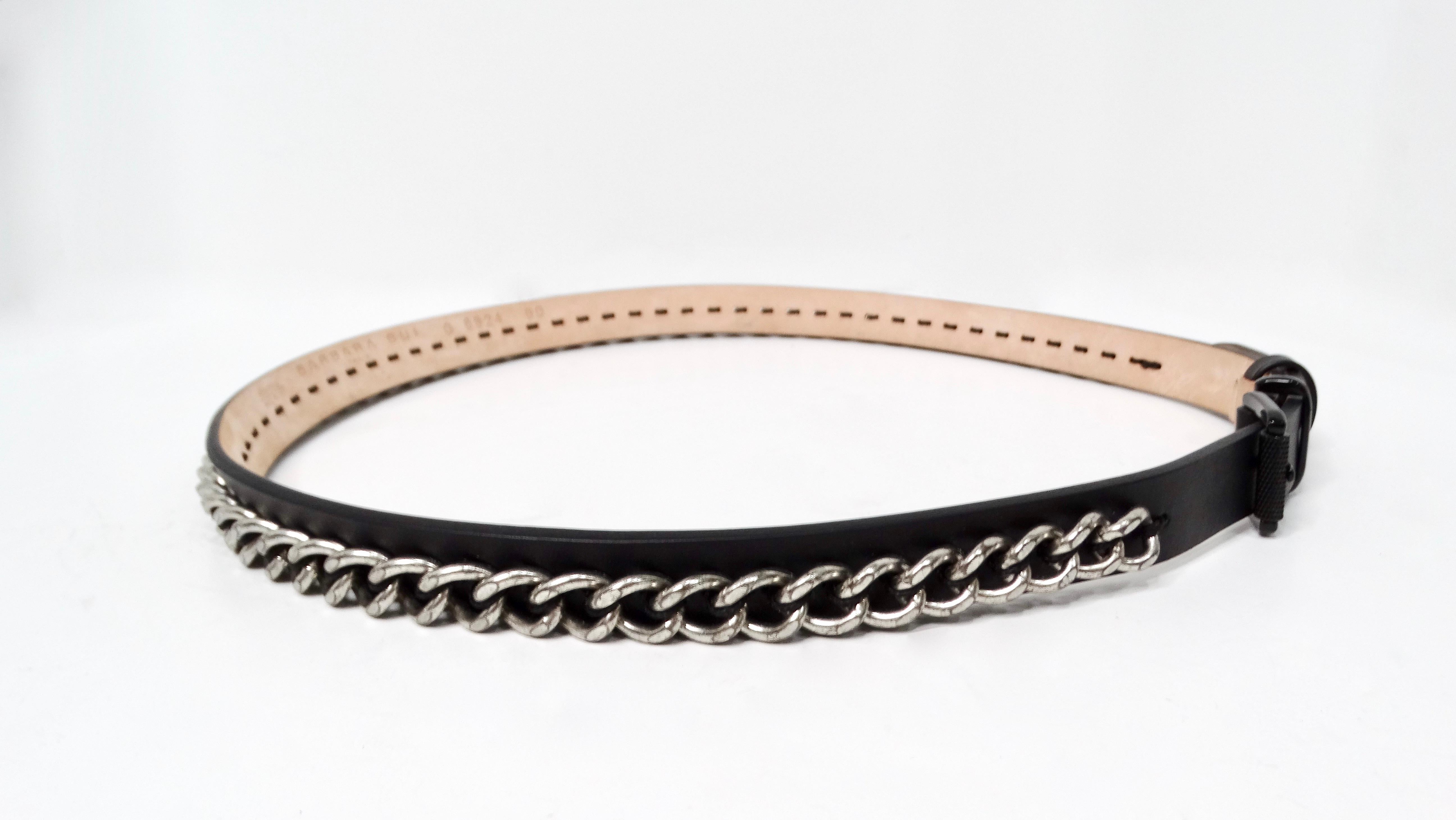 The Barbara Bui Black Buckle & Leather Belt with Silver-Tone Chain Detailing is a striking addition to any fashion-forward wardrobe. This sleek, skinny belt features a luxurious black-on-black leather design that exudes sophistication, complemented
