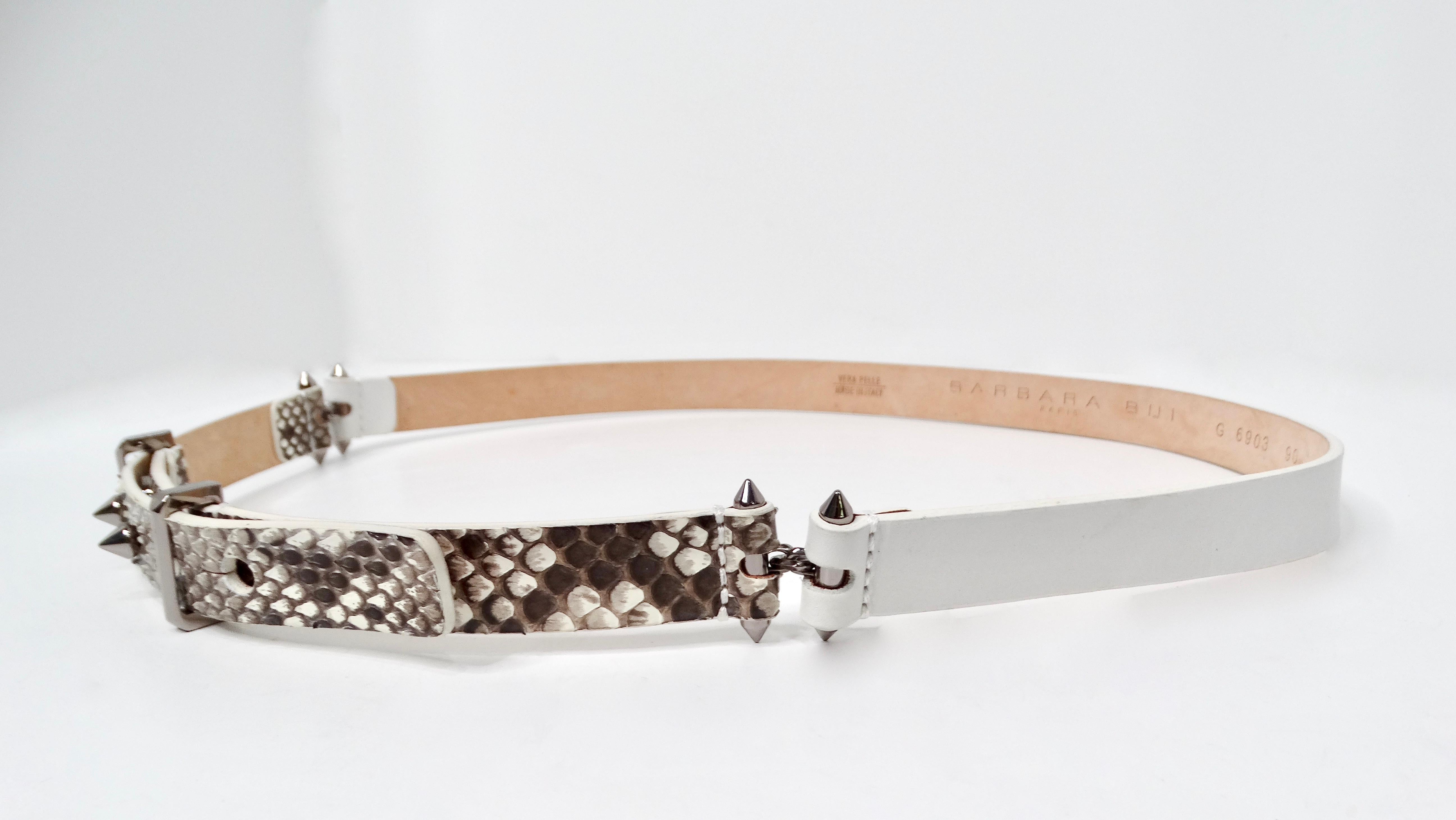 The Barbara Bui Skinny Snakeskin White Leather Belt with Silver-Tone Studs elegantly combines sophistication and edginess, making it an essential accessory for any fashion-forward wardrobe. Designed with a striking juxtaposition of white leather on