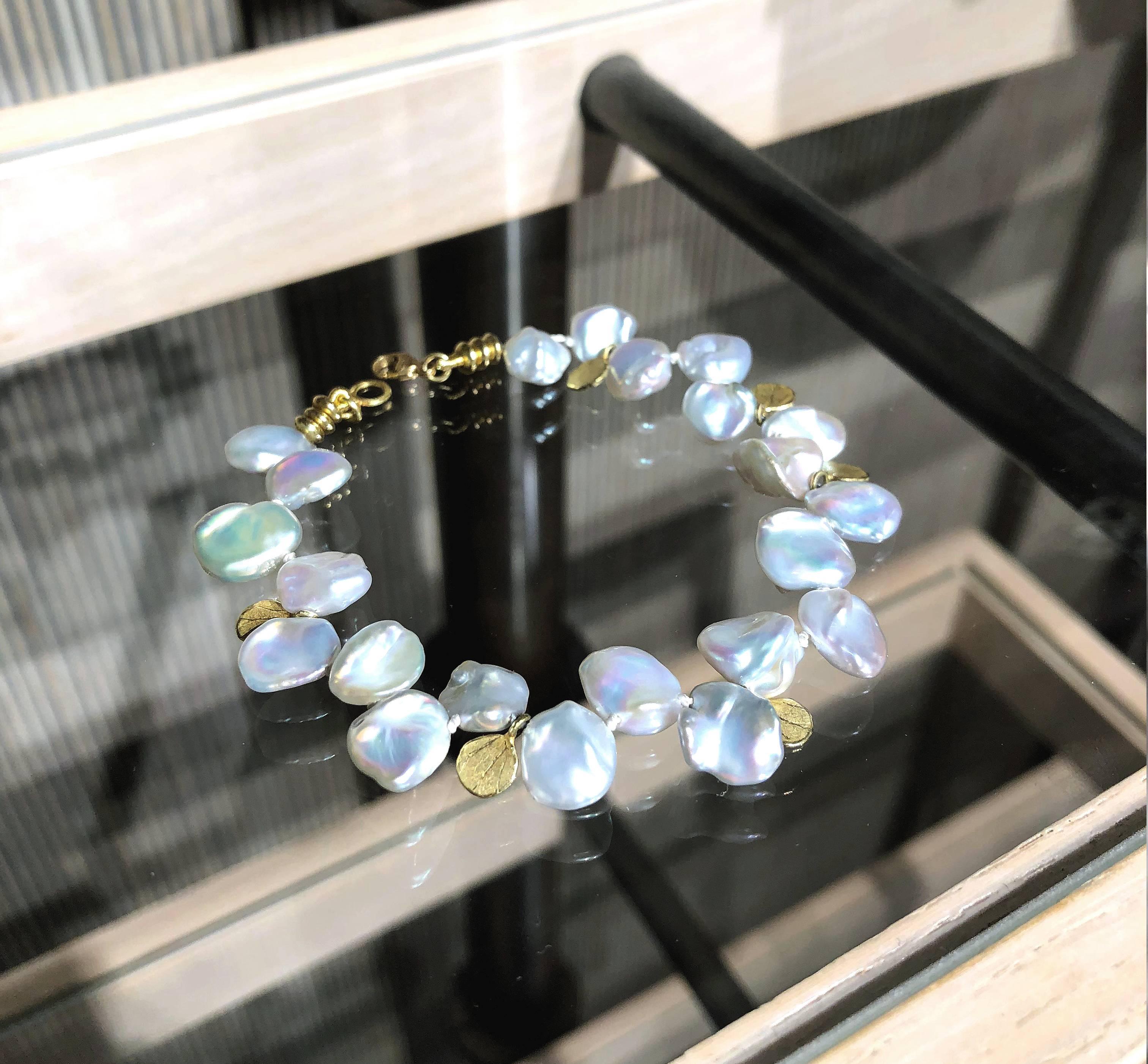 One of a Kind Bracelet handcrafted by award-winning jewelry artist Barbara Heinrich in 18k yellow gold featuring twenty-one lustrous silver blue keshi pearls accented with assorted 18k gold petal and bead charm elements. Stamped and hallmarked. 