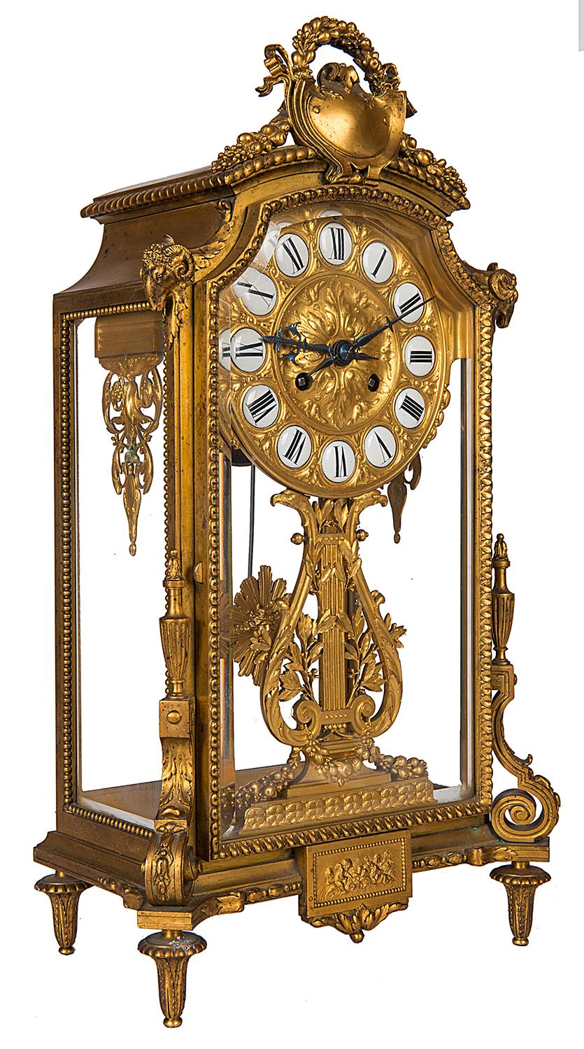 A fine quality Louis XVI style French gilded ormolu mantel clock, signed Barbedienne. Having shield and foliate decoration to the top, white enamel roman numerals, a lyre shaped pendulum, four glass sides, Rams head mounts and an ormolu plaque it