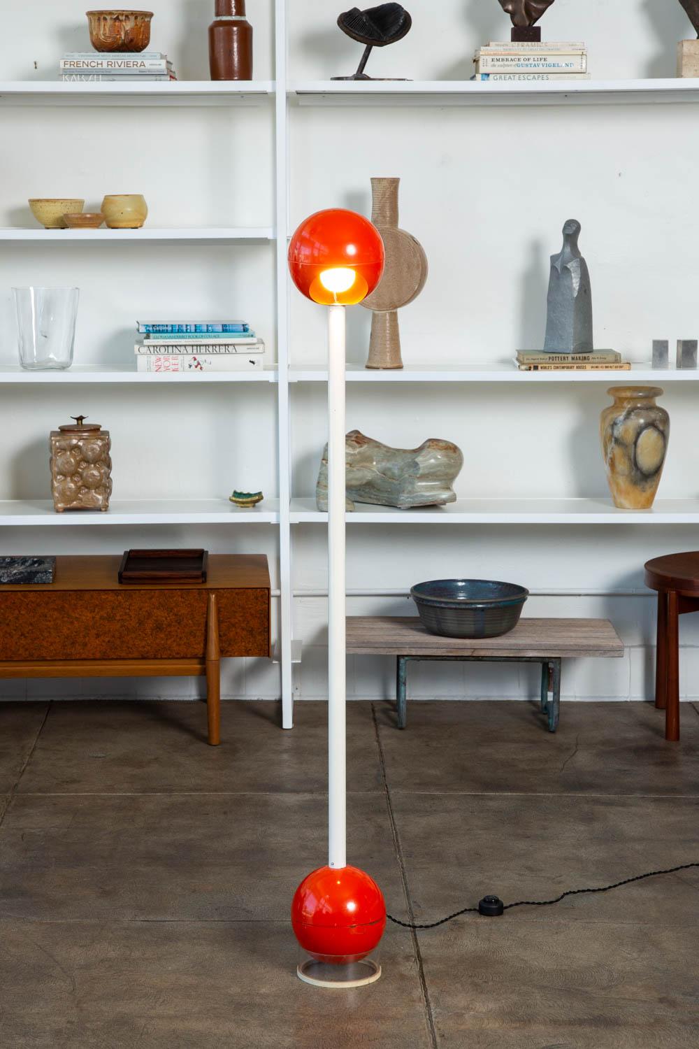 A rare Barbell floor lamp by John Mascheroni. This adjustable angle lamp features a sphere shape painted metal head and stem, that sit atop an opposing sphere that sits on a Lucite base. The lamp has been newly rewired with a black braided cloth