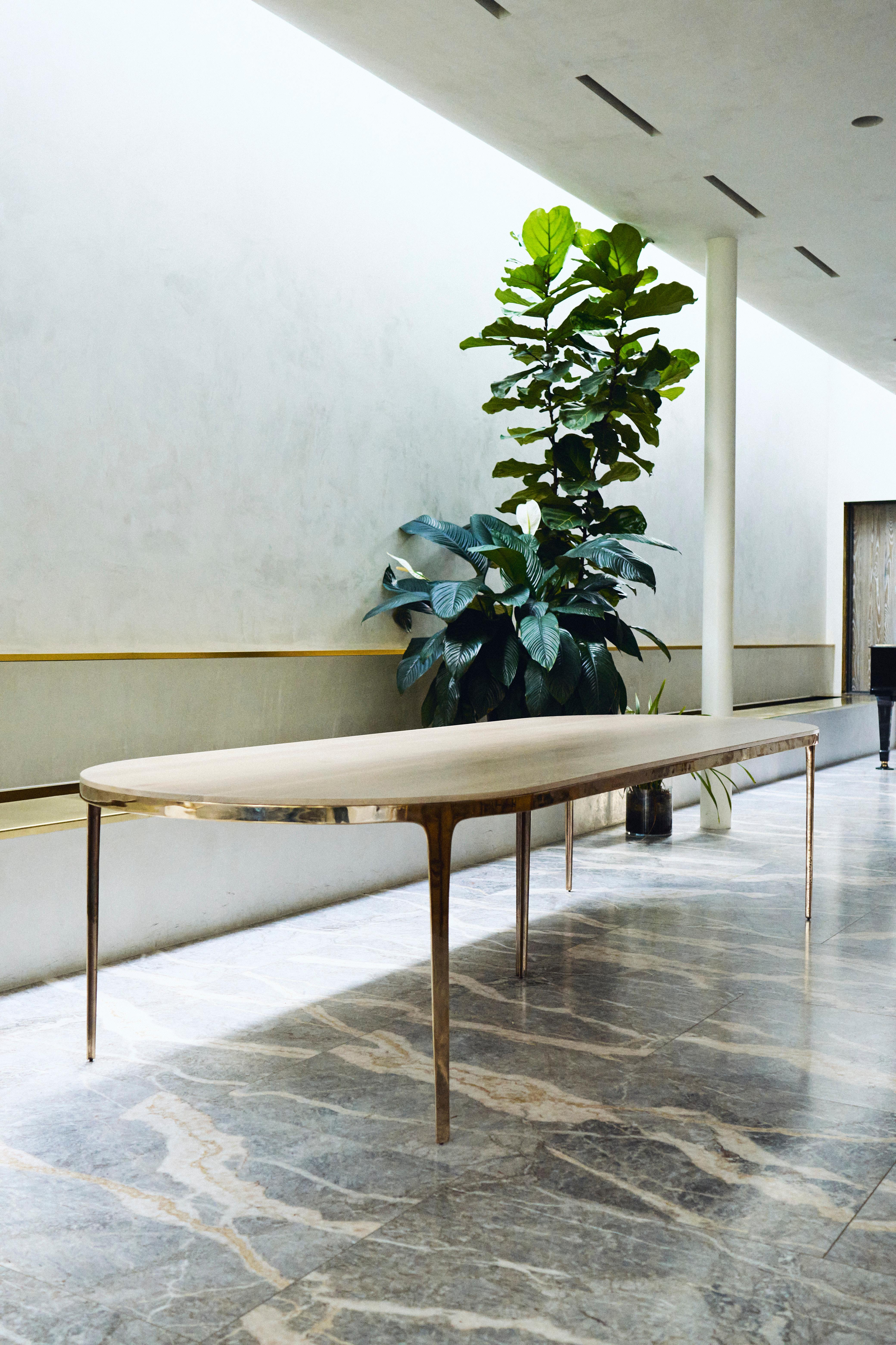Designed by Daniel Barbera, the 'Bronze' table is a Minimalist oval table consisting of Classic geometry on the exterior merged with organic flowing underside. The four legged sandcast solid bronze base is hand finished to a smooth mirror polish,