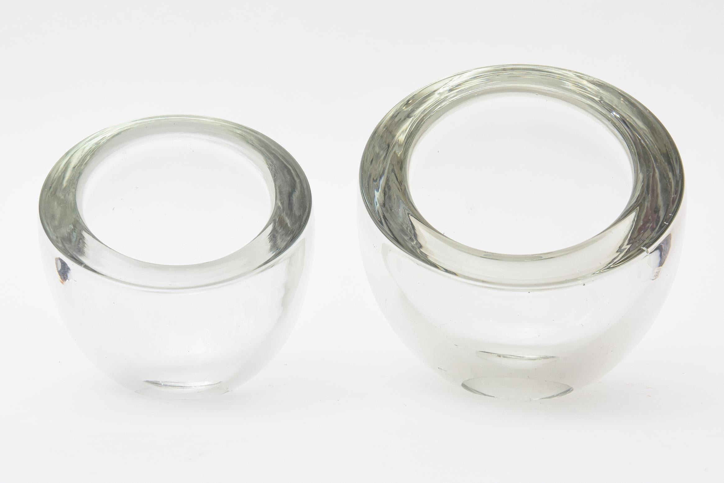 This sculpted pair of Italian Murano Barbini clear glass bowls are angled and tilted. That is the beauty. They can be used for a multitude of purposes and just to name a few would be flowers, candy, flowers, fruit, cosmetic uses and all serving