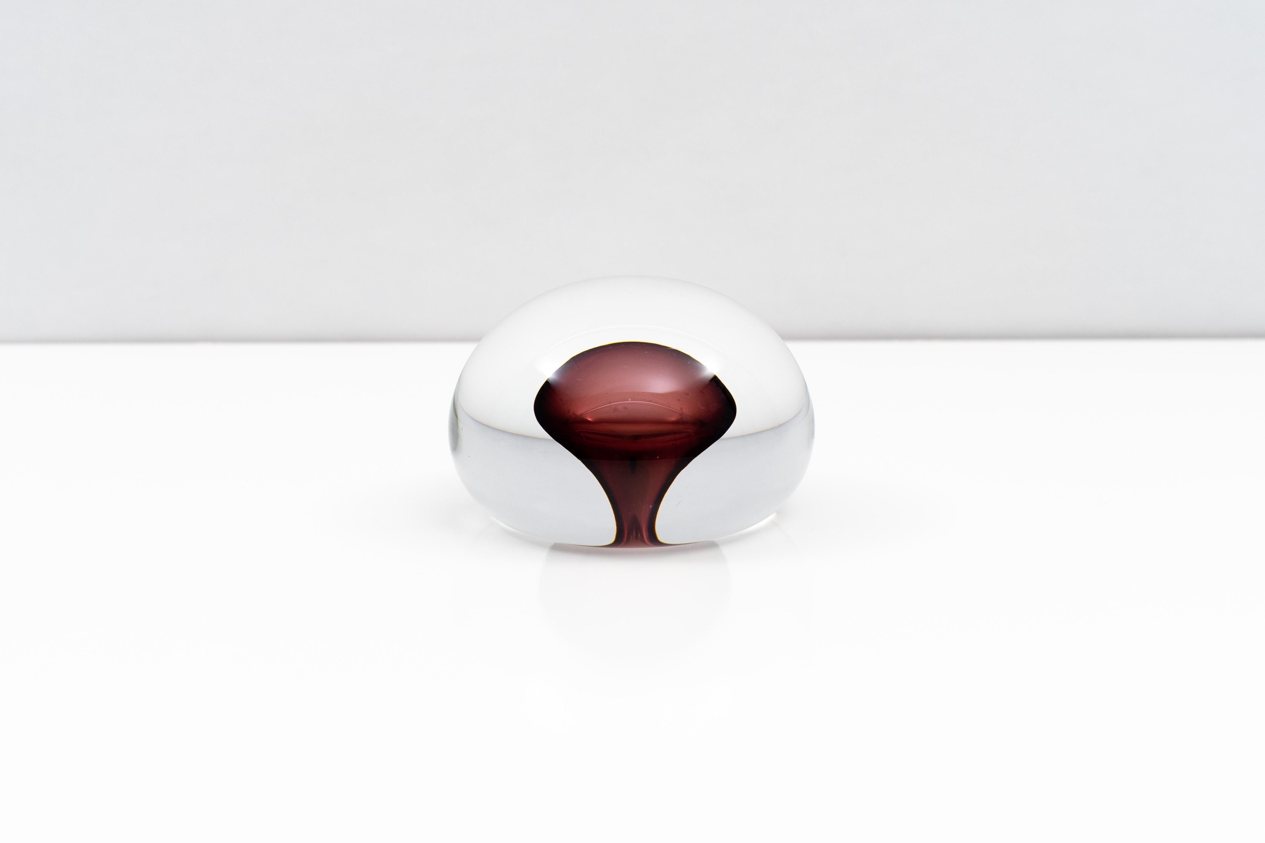 An impressively executed blown glass paperweight by Barbini Murano from around 1970. The crystal clear wide domed body magnifies any surface beneath it, while the shape of internal cased purple core dramatically changes depending on perspective.