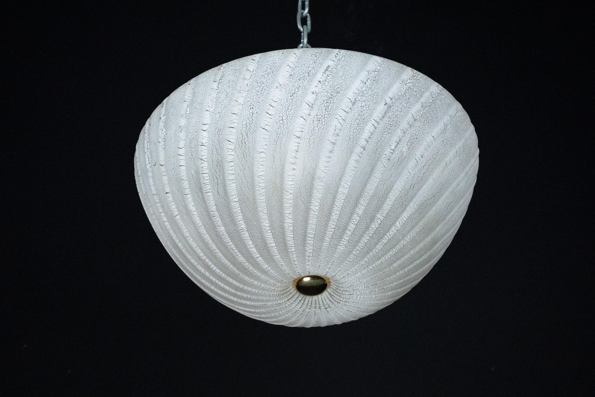 Elegante lampada da soffitto in vetro di Murano prodotta in Italia negli anni '80 da Barbini. La lampada è dotata di un grande paralume in vetro soffiato a mano con una superficie strutturata e scanalata in una morbida tonalità bianca smerigliata.