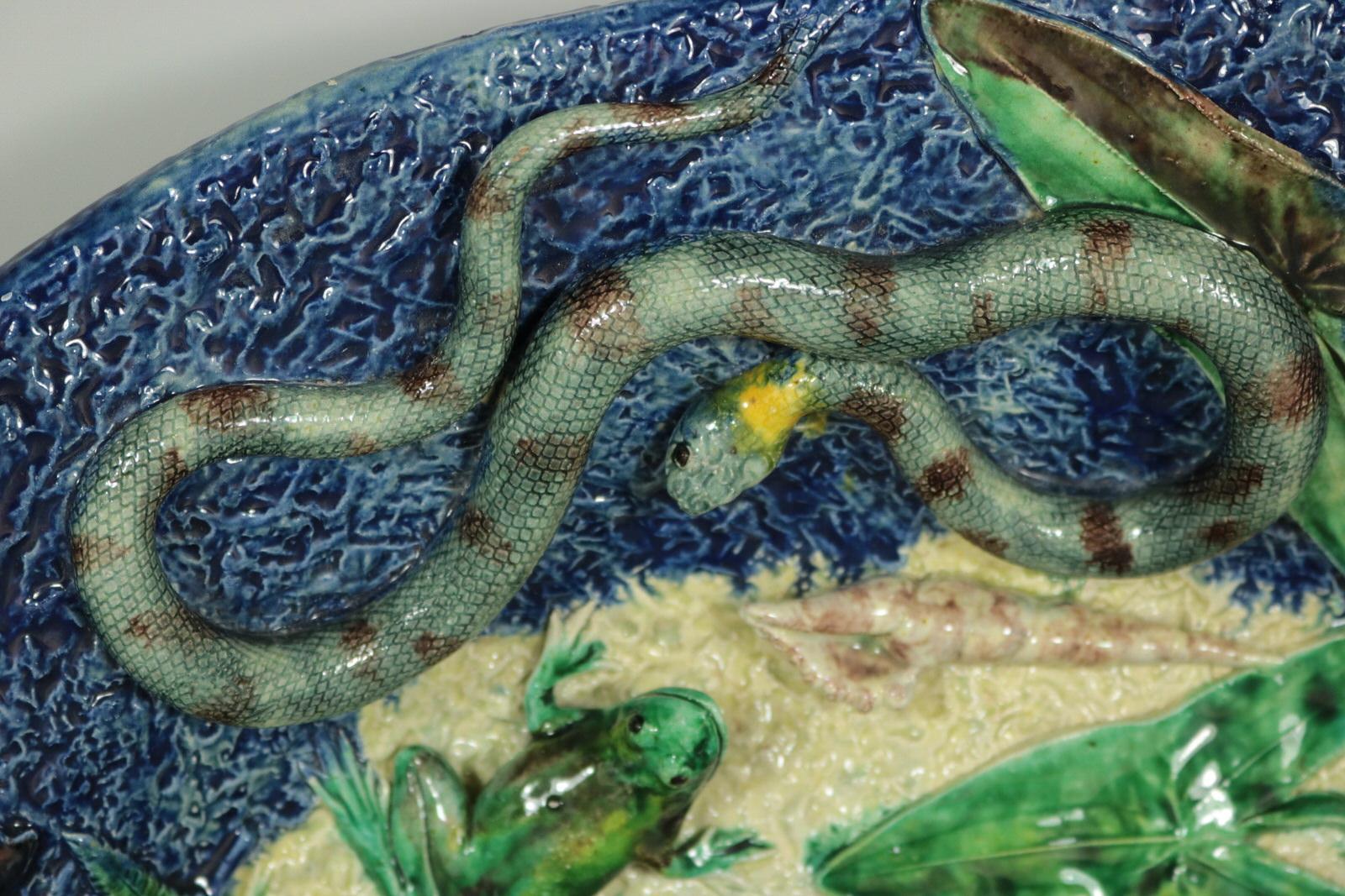 Plat mural Barbizet en majolique de Palissy français qui présente des poissons (dont un brochet), un serpent, un lézard, une grenouille, une tortue, des insectes, des coquillages, des mûres et des feuilles. Coloration : bleu, vert, crème, sont