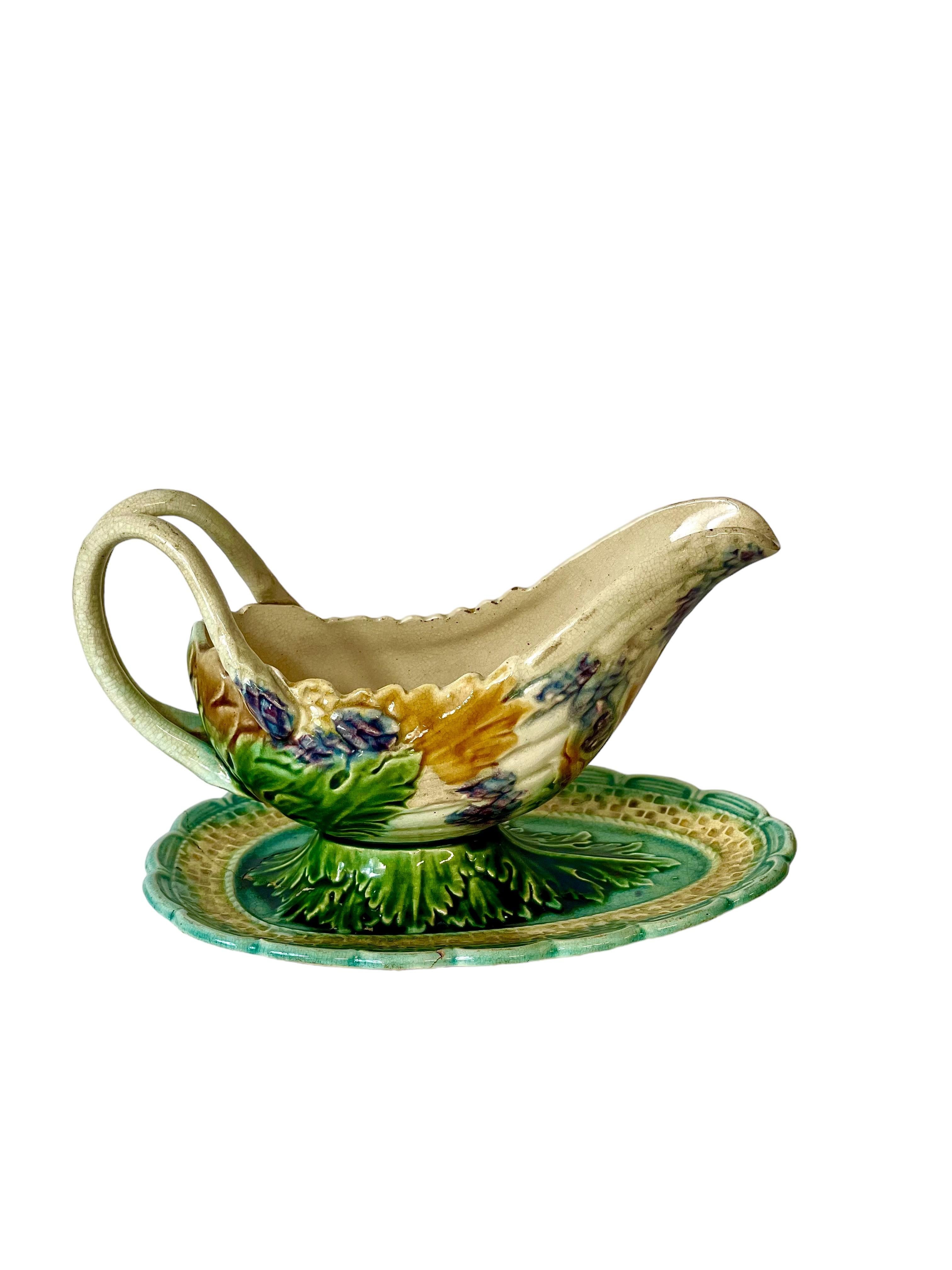 An interesting and unusual French Majolica barbotine asparagus 'Saucière' on a shaped, attached stand. The body of the 'boat' is formed from a bunch of purple-tipped asparagus spears, swathed in green and mustard yellow leaves, while two delicately