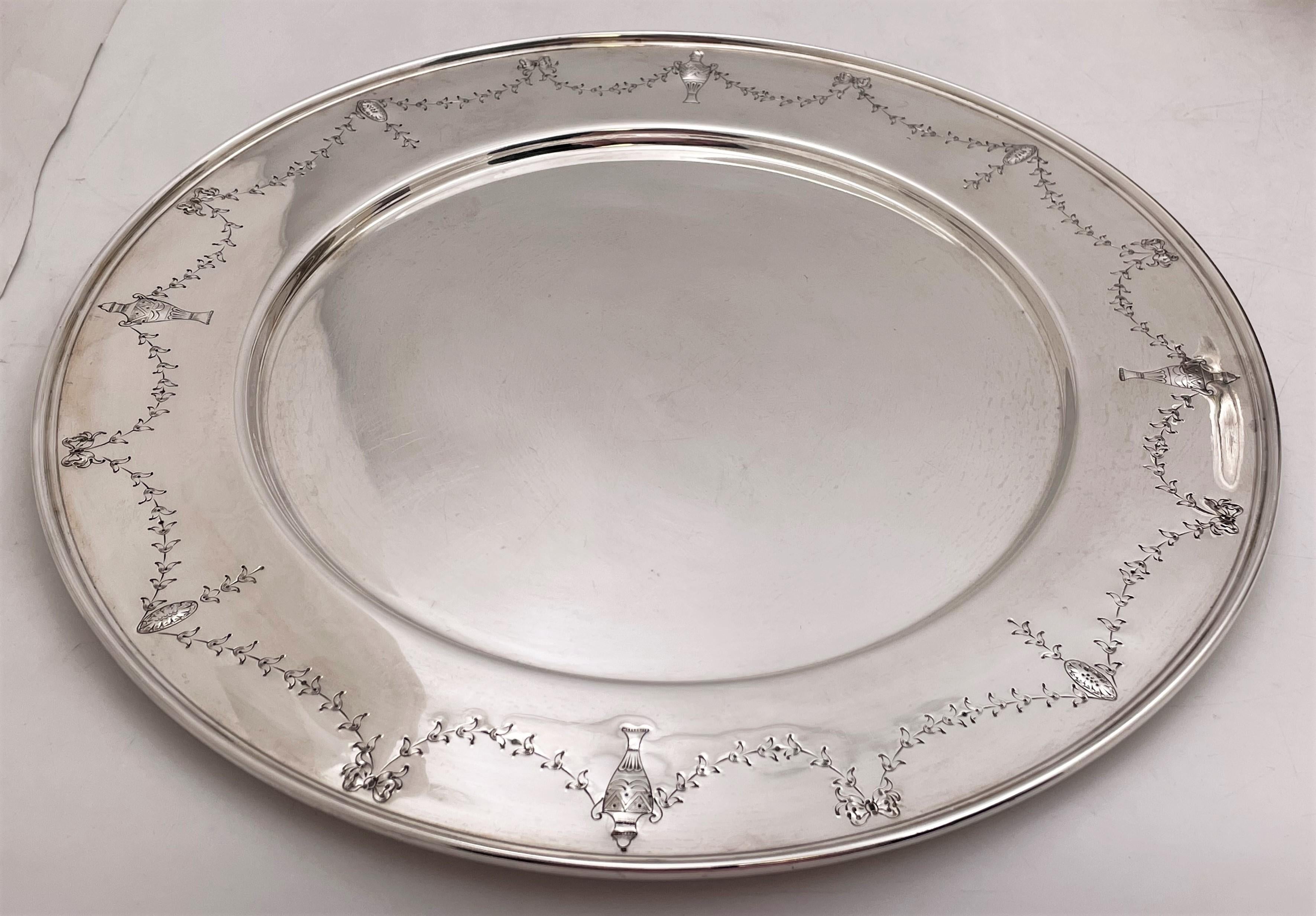 International Sterling/ Barbour & Co. set of 12 sterling silver dinner plates or chargers in the Orange Blossom pattern number 1319C from the early 20th century. Each measures 12'' in diameter by 3/8'' in height and bears hallmarks as shown. Total