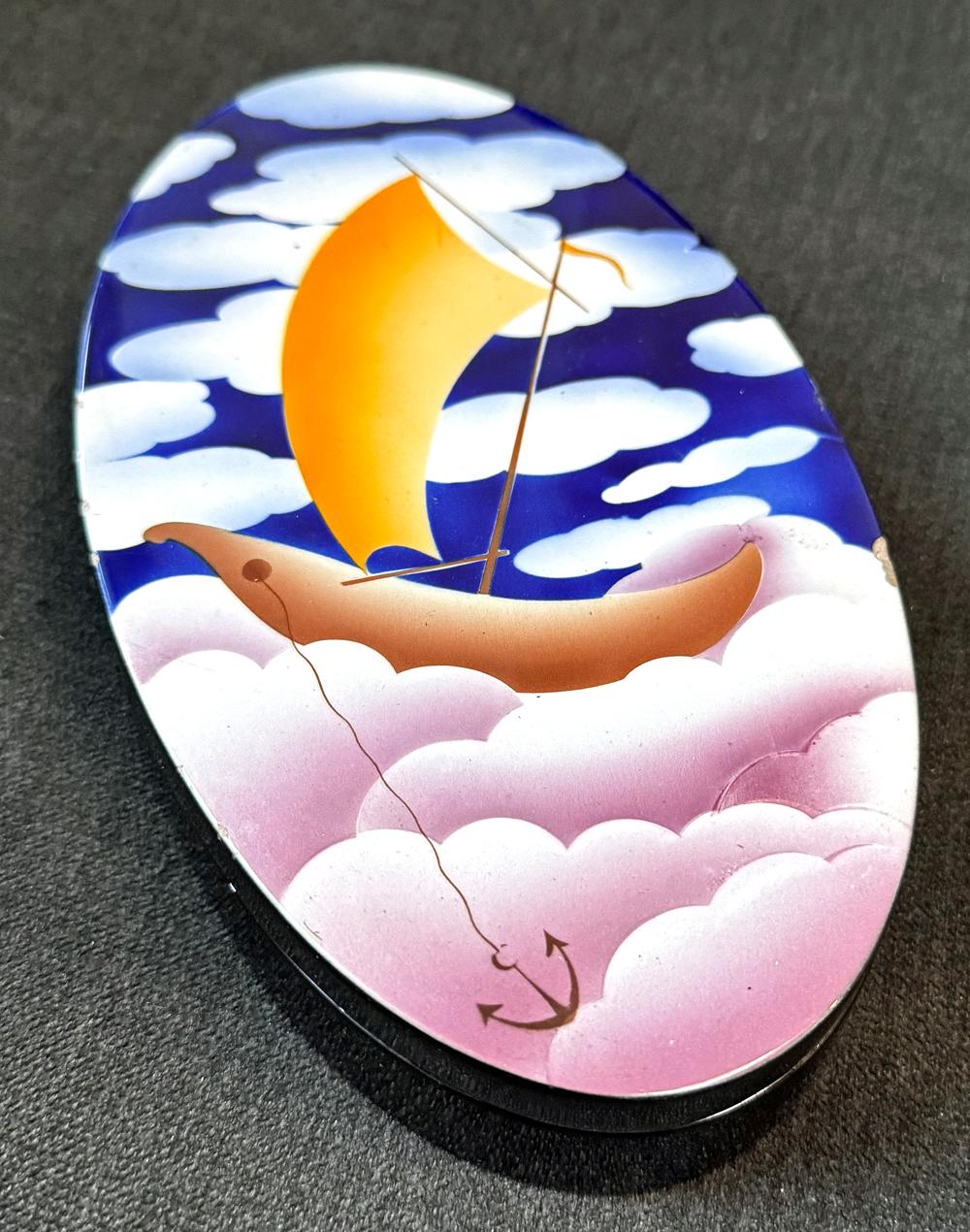 An extraordinary example of high style Art Deco design by one of Italy's masters in the 1930s -- Angelo Simonetto -- this covered, oval ceramic box depicts a golden barc or sailboat floating in a deep blue sky filled with purple-tinged clouds. 
