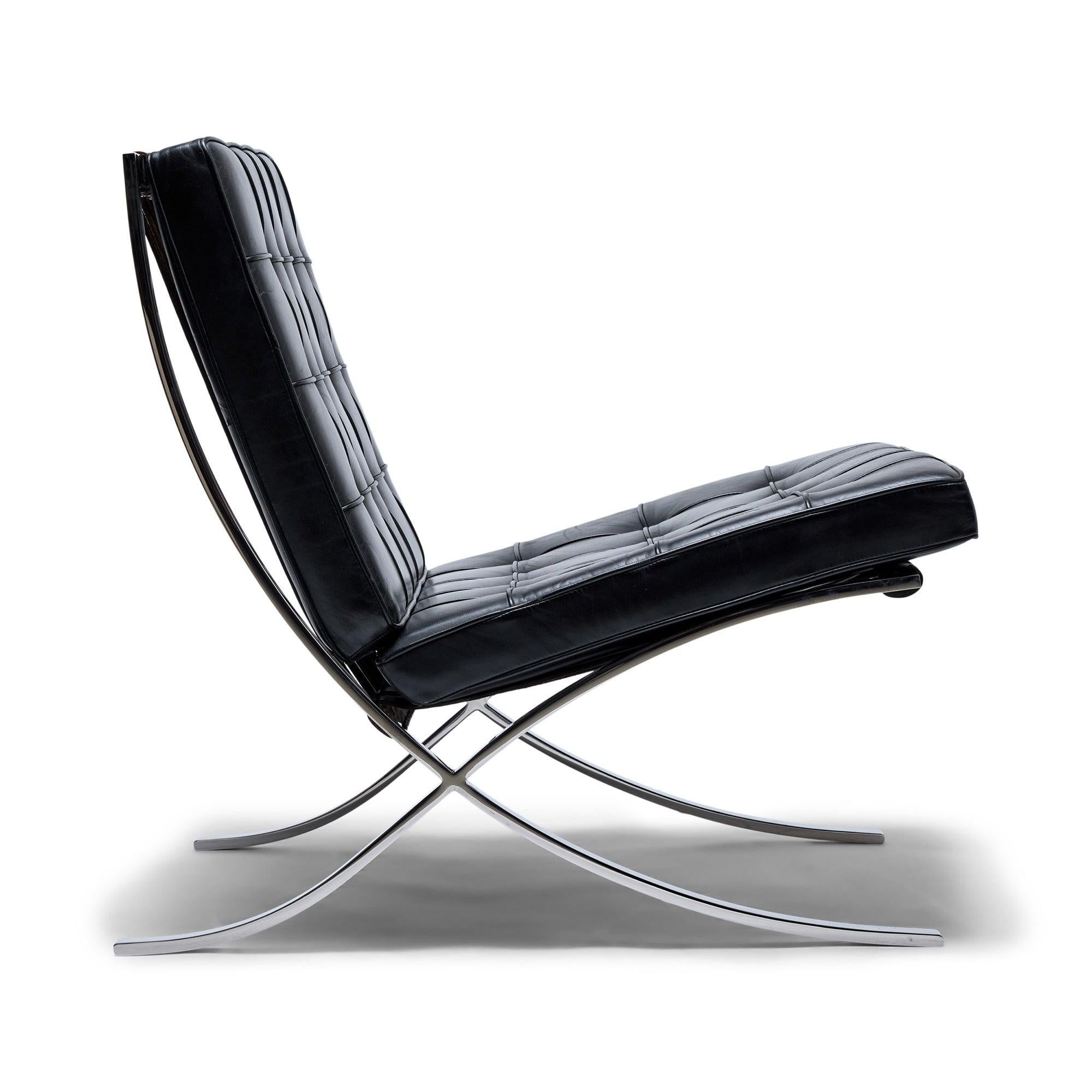 A 'Barcelona' chair, with the original black leather upholstery and belting straps on a chromed steel frame.