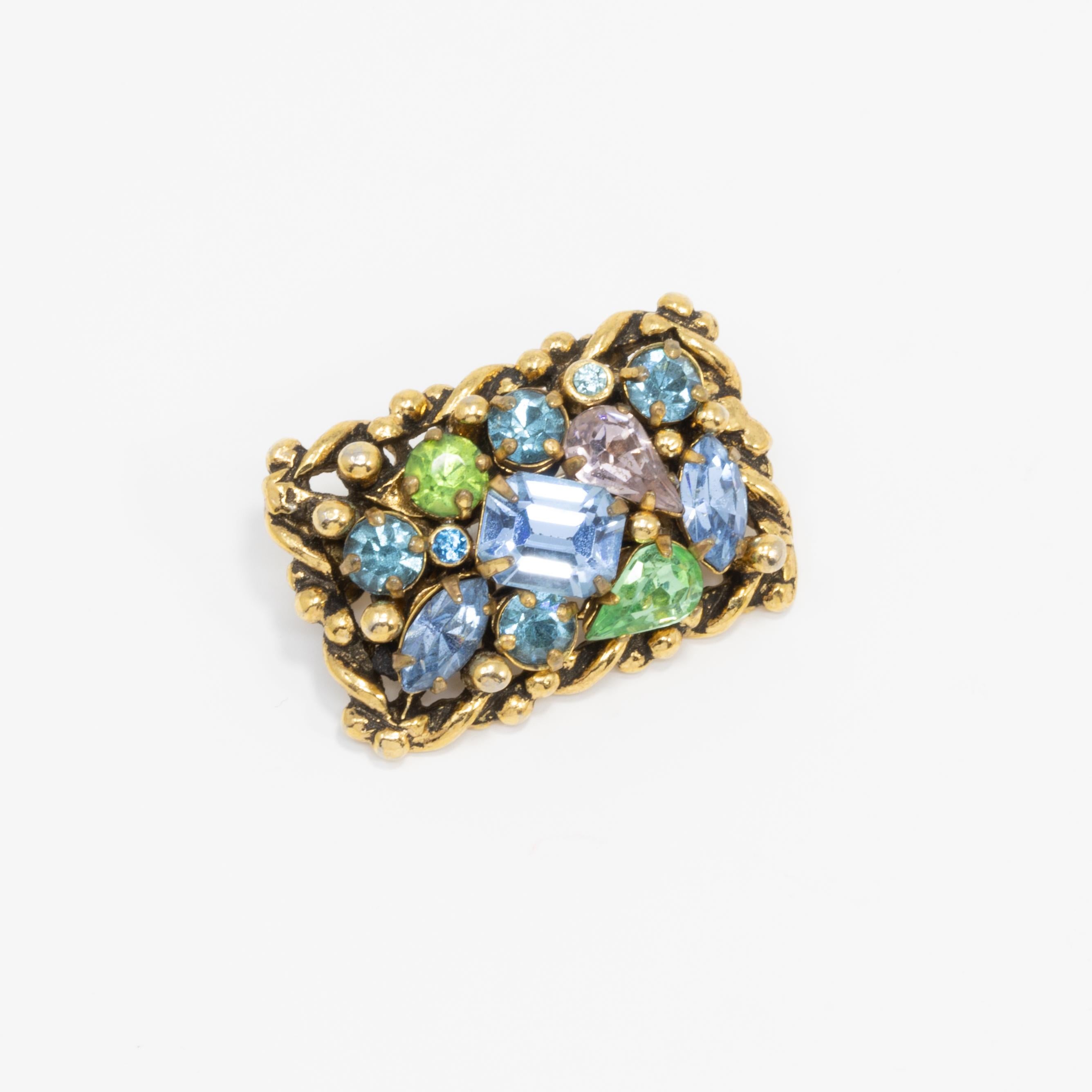 Vintage pin by 1950s costume jewelry designer Barclay, based in Rhode Island, USA. Features aquamarine blue and peridot green crystals prong-set in a decorative, gold-tone metal setting.From the Jewels of India collection.

Hallmarks: Barclay