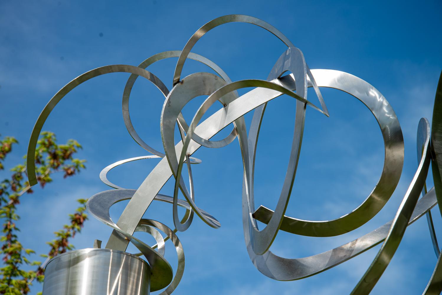 Diese elegante abstrakte Skulptur stammt von den Künstlerinnen Ann Bartok und Olena Kassian aus Toronto. Fein gewundene Bänder aus Edelstahl sitzen auf einem großen Zylinder, der das Sonnenlicht reflektiert. Bartok und Kassian, die seit ihrer ersten
