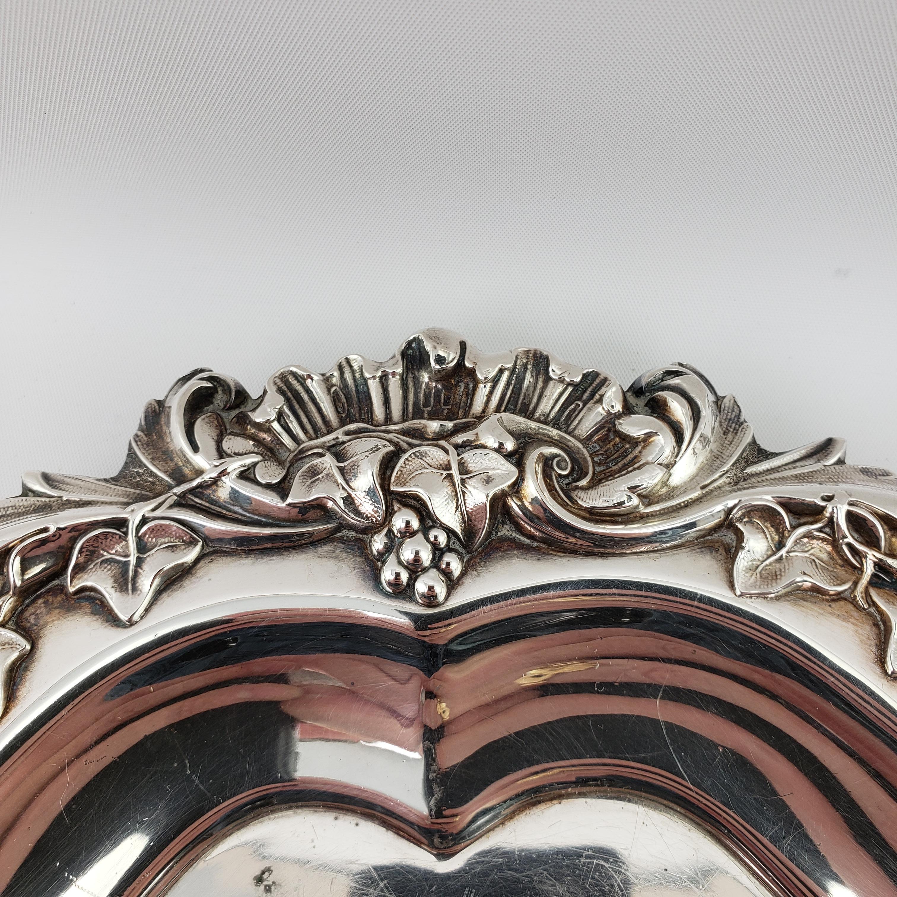 Ornate silverplated serving tray featuring dual handles, a hand chased center and a raised border featuring scrolling floral and foliate designs. This is a fairly substantial tray which is quite large and heavy.