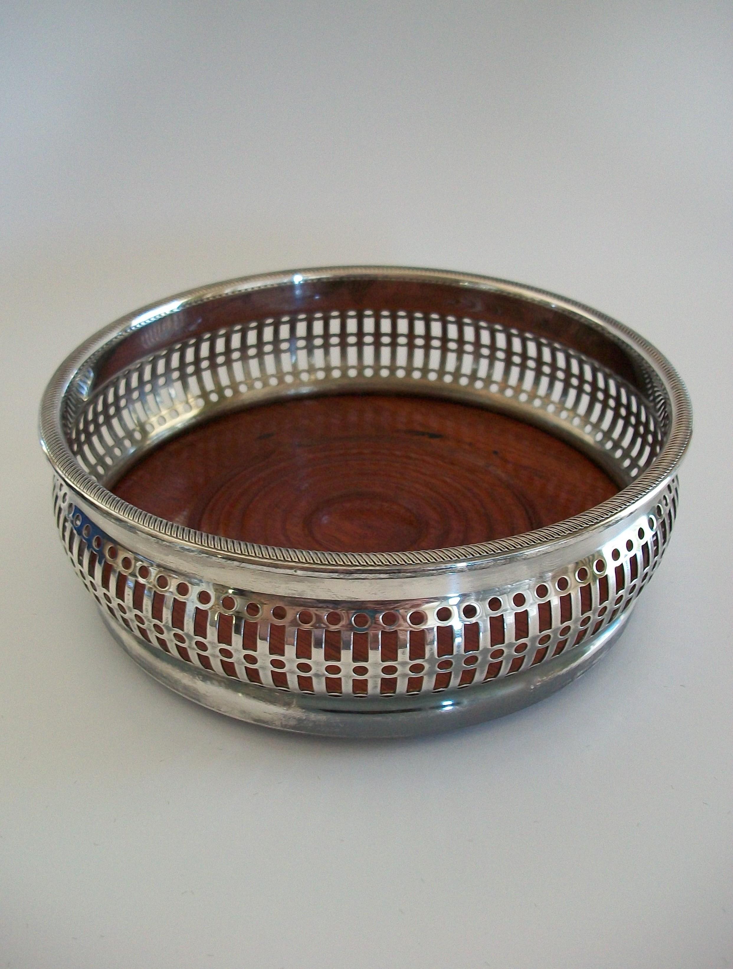 BARKER ELLIS - Quality silver plate on copper bottle coaster - featuring a Regency style pierced border and rope twist rim with a turned wood insert - green velvet liner to the underside - original retail presentation box - signed on the base -