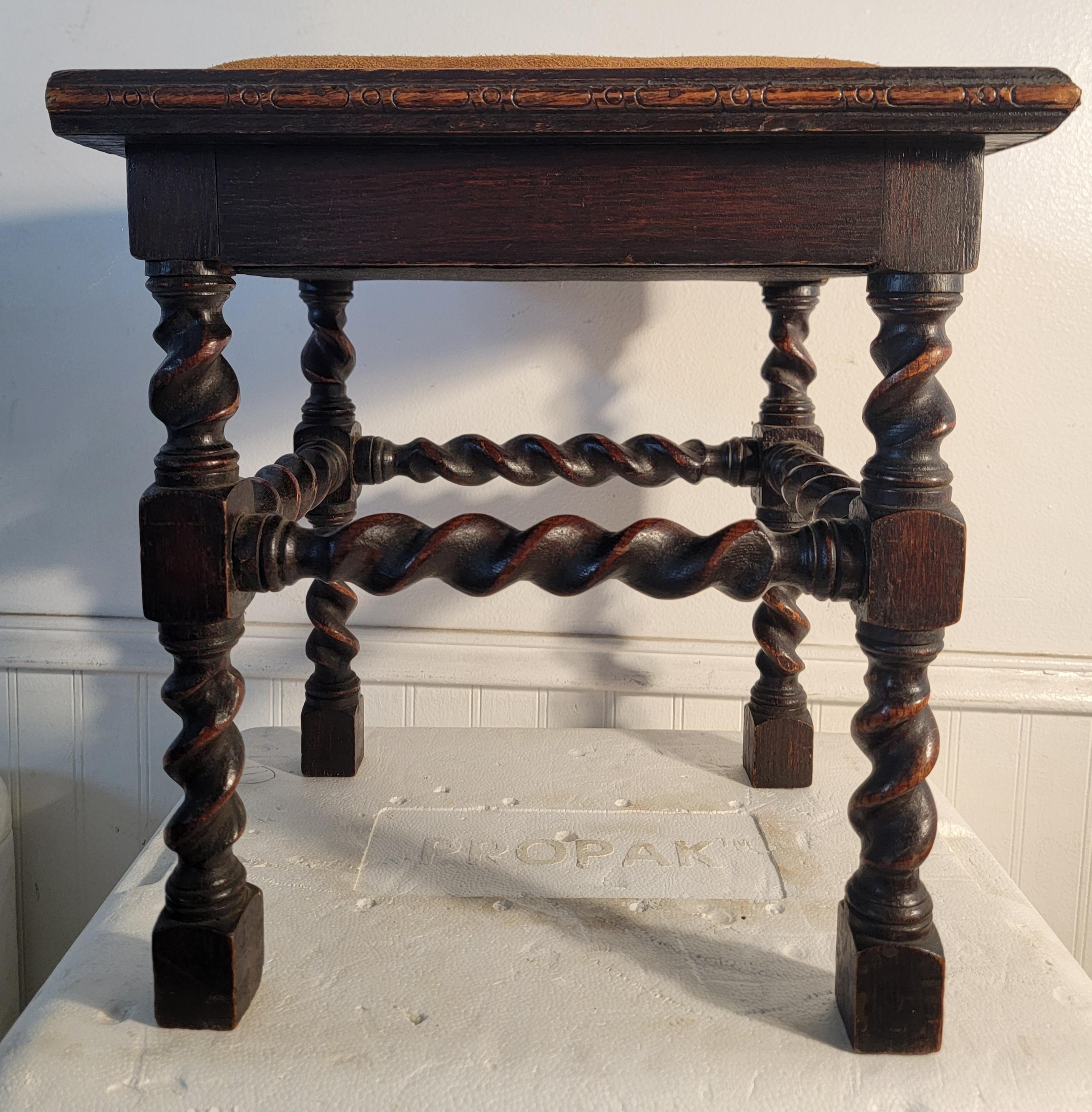 Early 20thc barley twist stool or bench with a leather seat cushion on the top of the bench. Wonderful construction and wonderful age. This twisted legged bench with a wonderful stain/patina, this is a wonderful piece. 