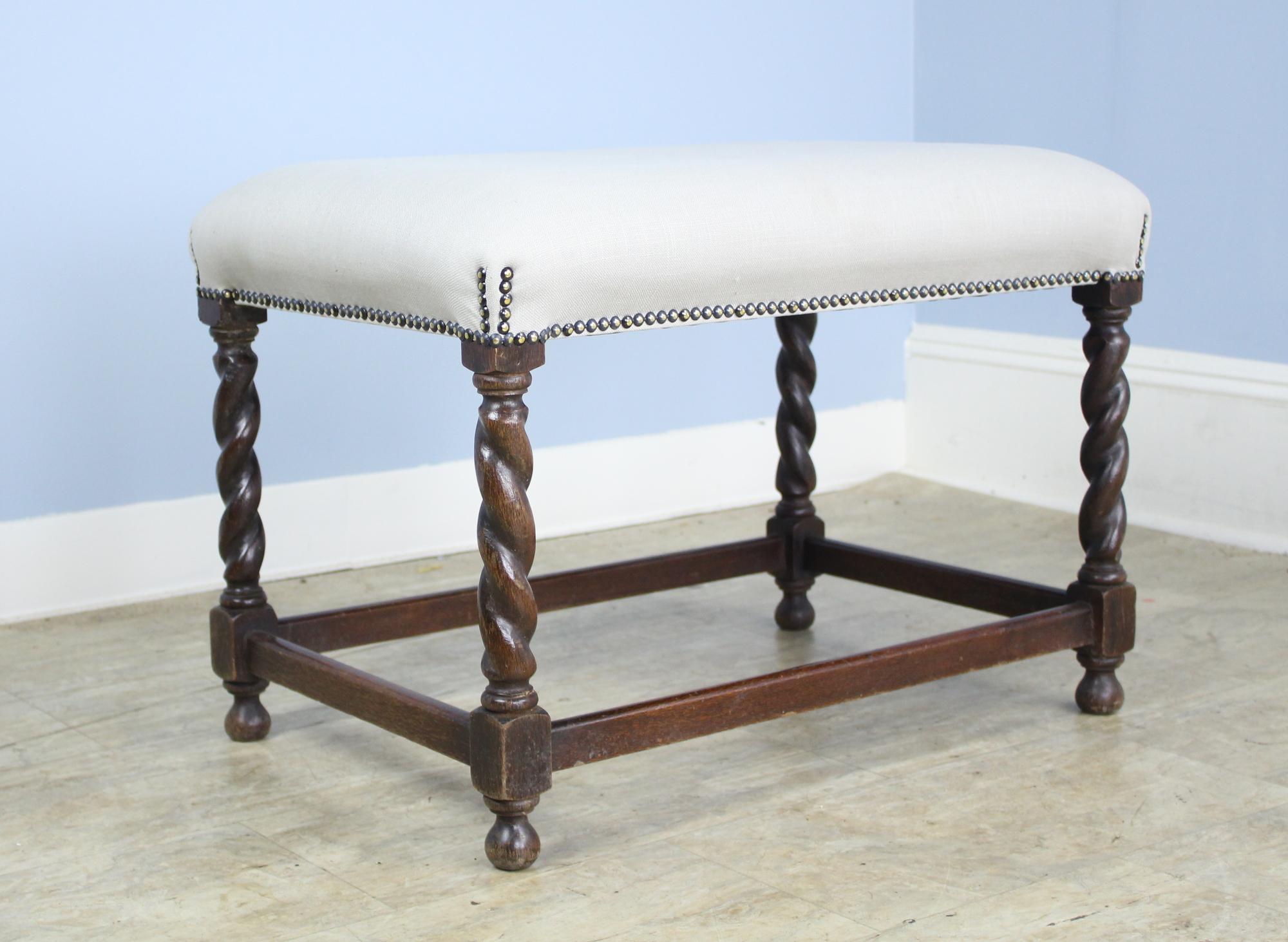 A small stool or bench with visually arresting oak barley twist supports. Good nailhead detail where the seat meets the legs. Newly upholstered in gray linen to be used as is or reupholstered. Charming!

 