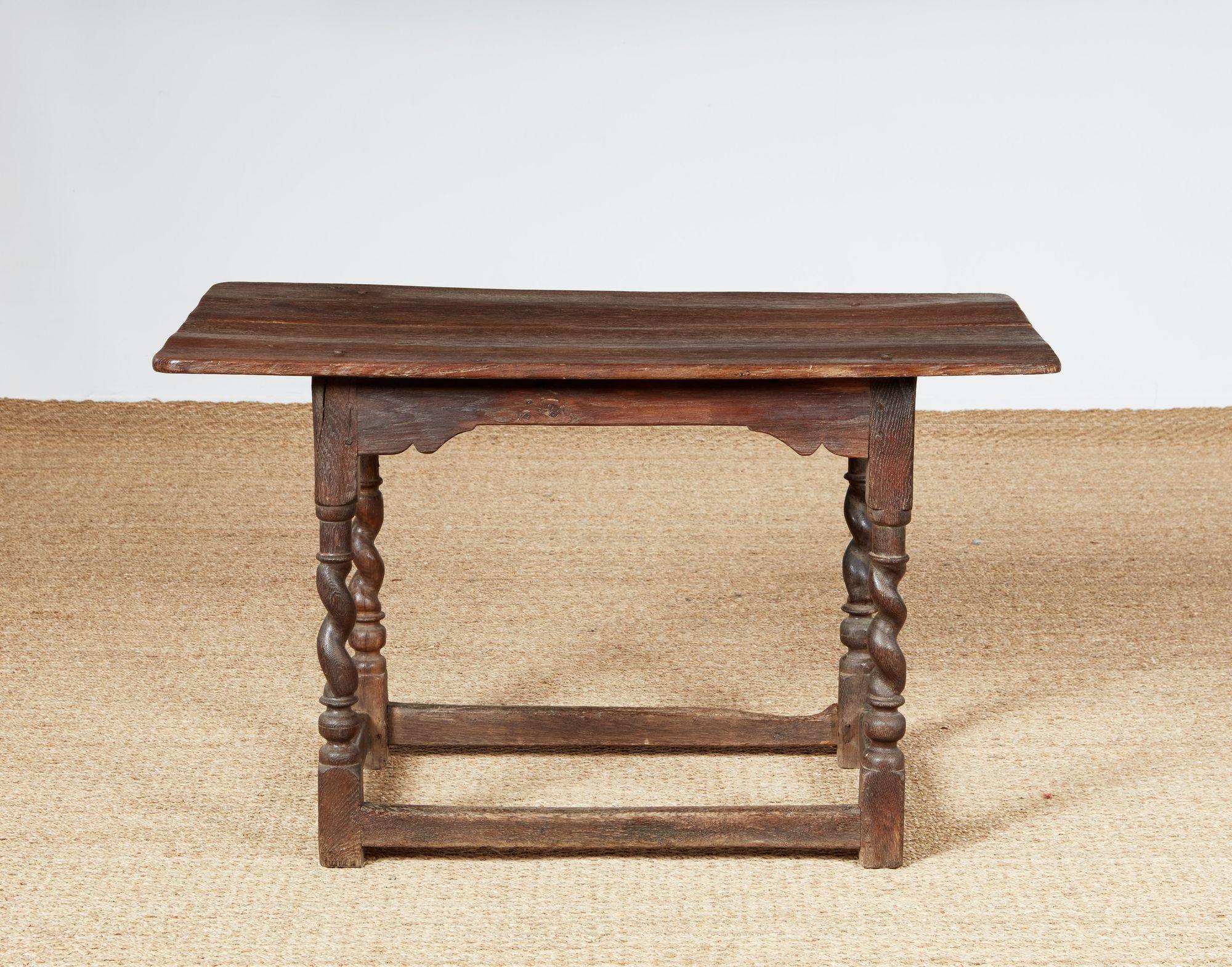 Table centrale ancienne en chêne avec un plateau rectangulaire aux coins arrondis sur un tablier étroit avec des consoles d'angle intégrées. La table repose sur des pieds tournés en torsion d'orge au-dessus d'un châssis à caisson bas de section
