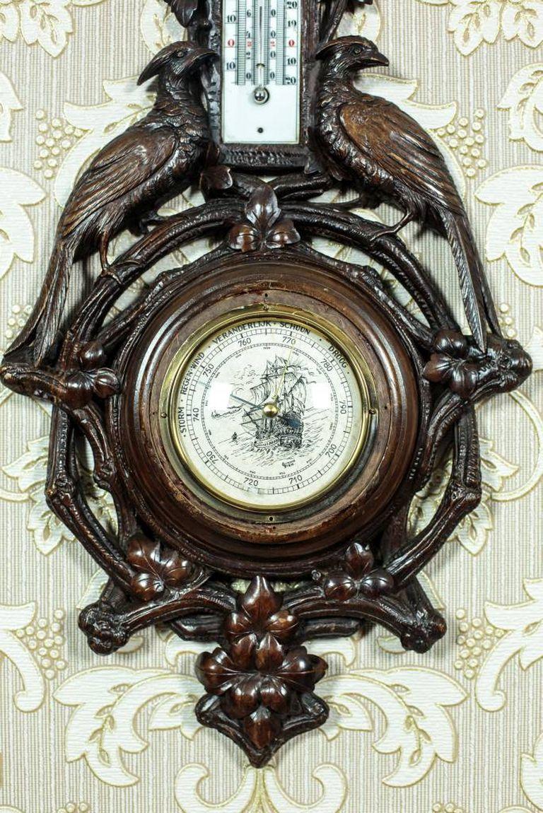 We present you this barometer in a walnut, openwork case of the extended form.
The whole is ornate with a semi-plastic sculpture with the motif of vine and two peacocks holding a high finial.
There is a groove for a wall thermometer in the