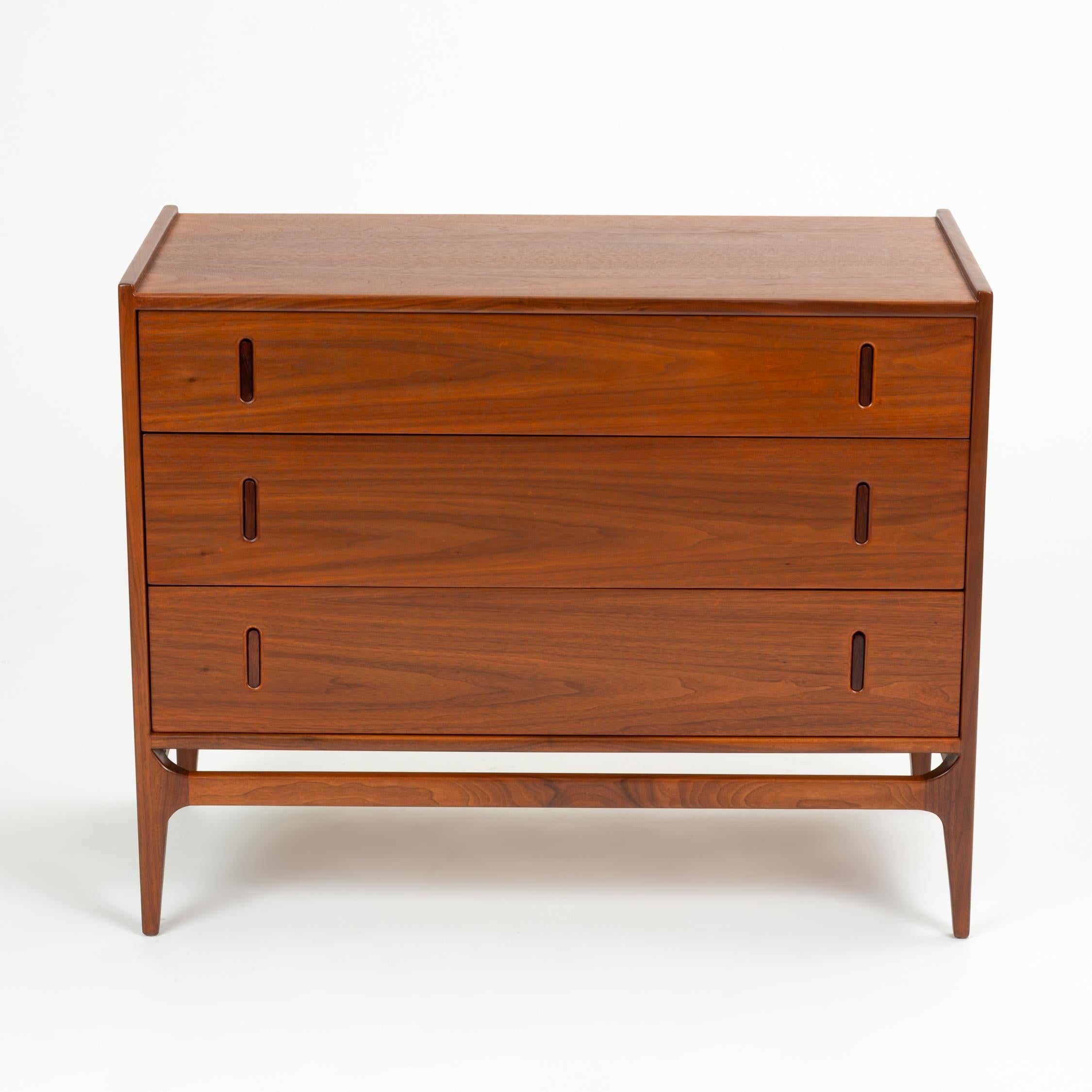 A compact dresser from Richard Thompson’s Baronet collection for Glenn of California. A stylish grouping in walnut, the Baronet case pieces are defined by their floating apron across the front two legs, raised end pieces on the case, and recessed