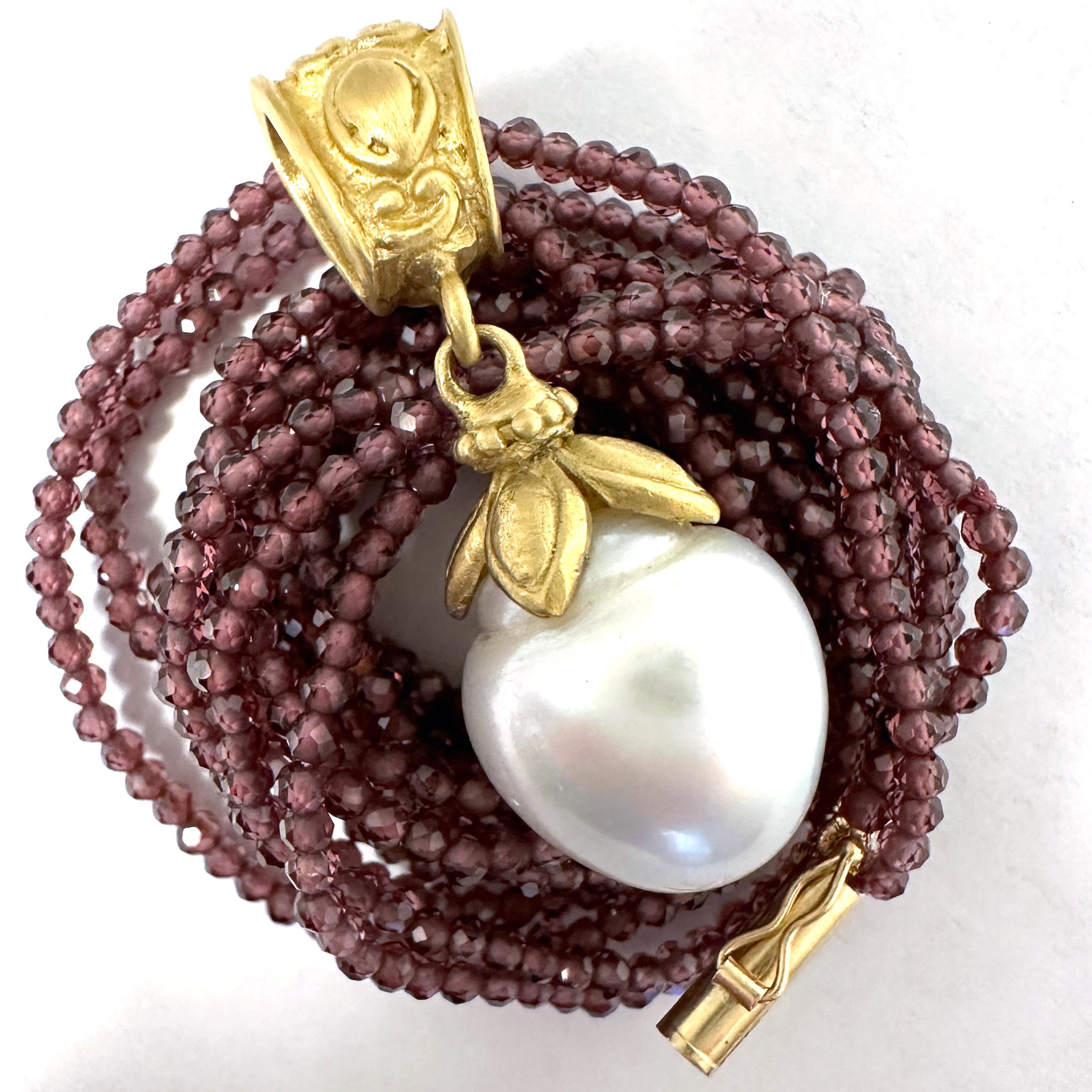 This lustrous white South Sea baroque pearl is set in a Byzantine-flavored, satiny 18 karat yellow gold two-part pedant handmade in our shop by Eytan Brandes.    

The pearl has a graceful egg shape with a pronounced ridge at the top, mostly