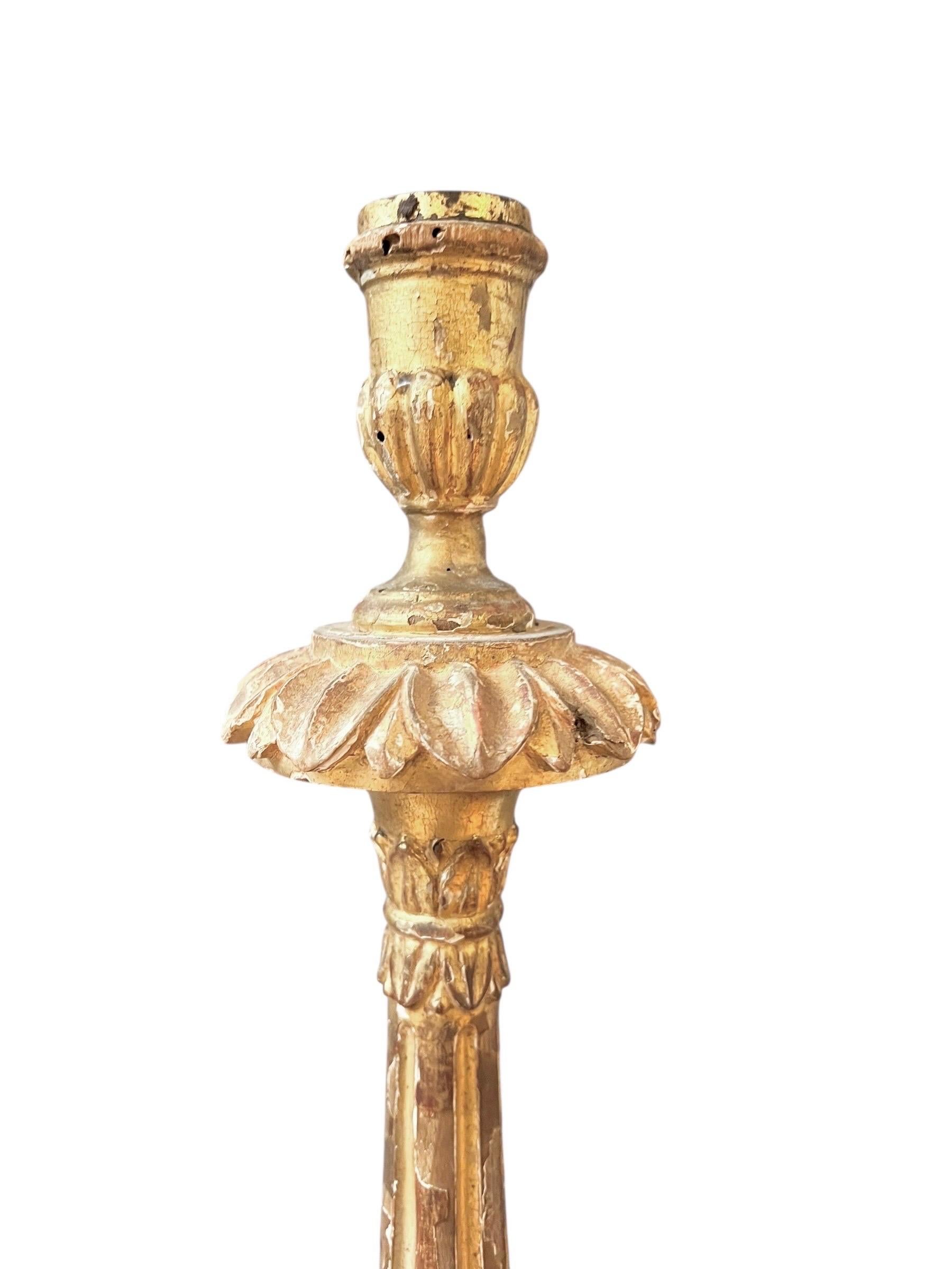 Impressive Baroque altar candlestick finely carved in wood and gilded with gold leaf.
The piece stands on a tripod base with lion paw feet, supporting an elegant baluster stem adorned with fluted motifs and acanthus leaves, surmounted by a wide