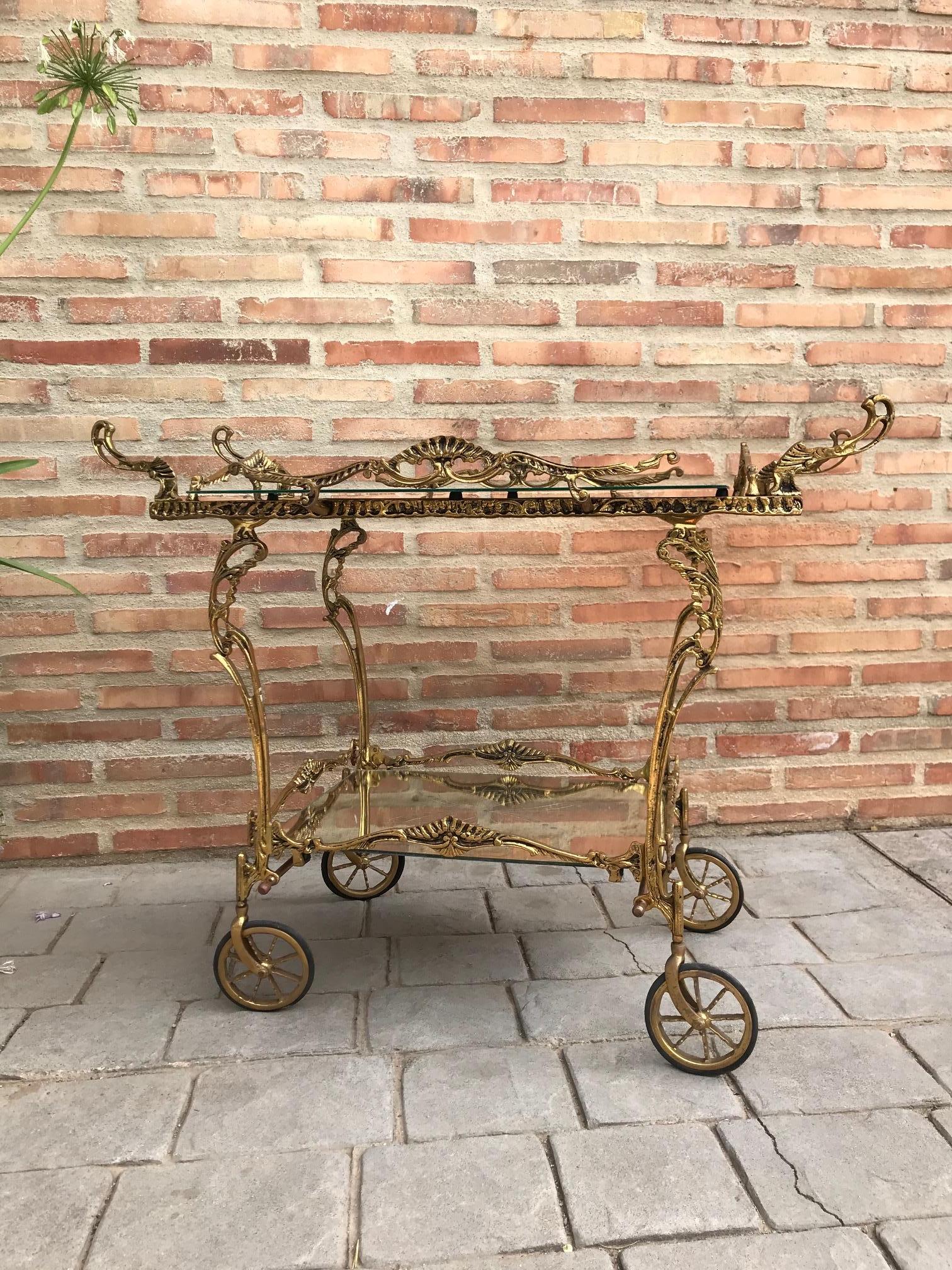 Stunning Baroque style brass bar cart with a mirror top and carved mirror bottom shelf. Cart has beautiful detail. Trolley.