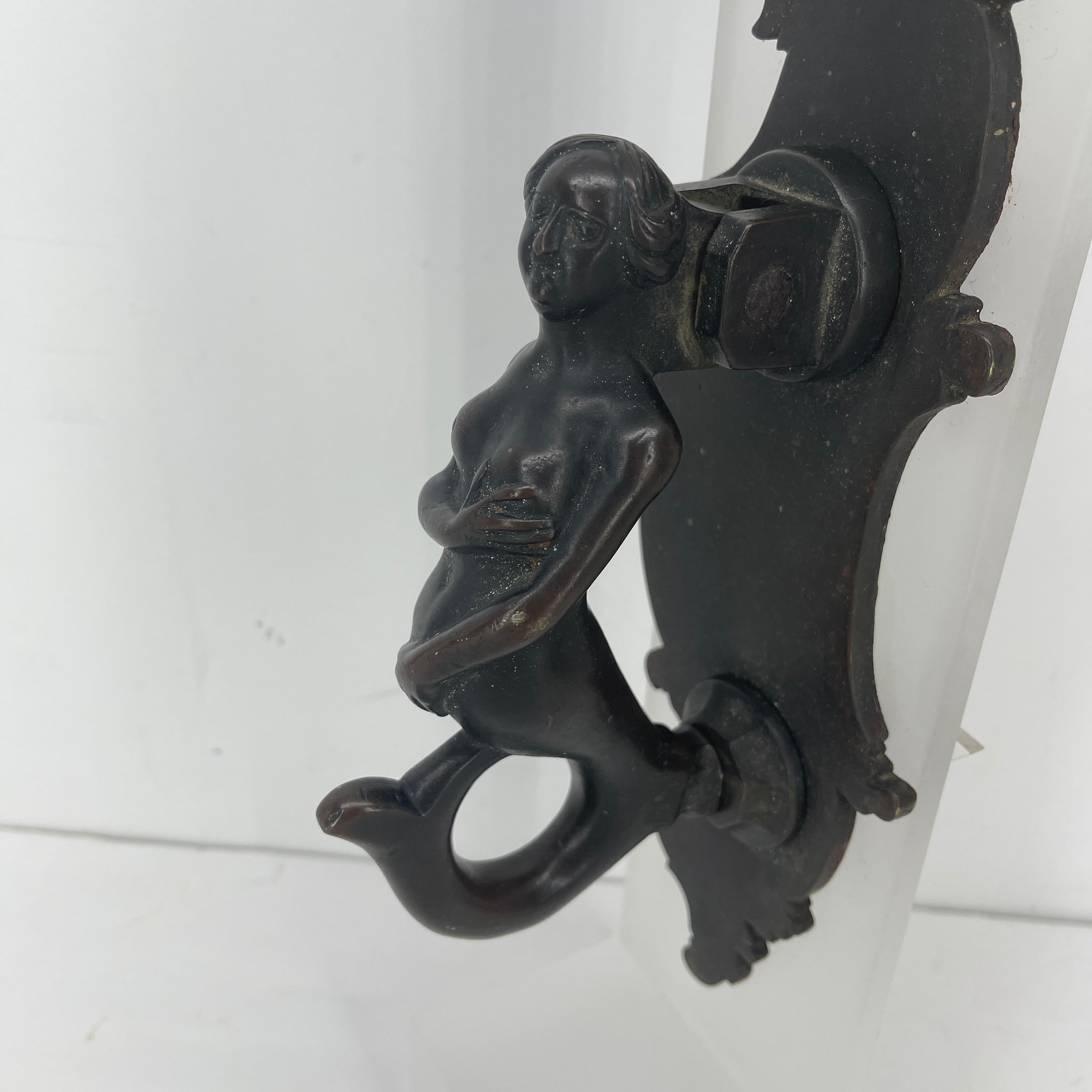 Early German baroque bronze mermaid door knocker on frosted lucite stand.
This door knocker is a work of art; heavy bronze with original patina, hand crafted figure of a mermaid with expressive face and body, and mounted to thick lucite stand. With