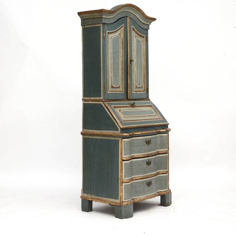 Baroque secretary /bureau in two parts.
Upper cabinet with curved top, pair of doors with marked profiled fillings.
Top of the doors is followed by the top of the bureau.
Bottom with slanted writing flap and marked profile filling.
Small drawers