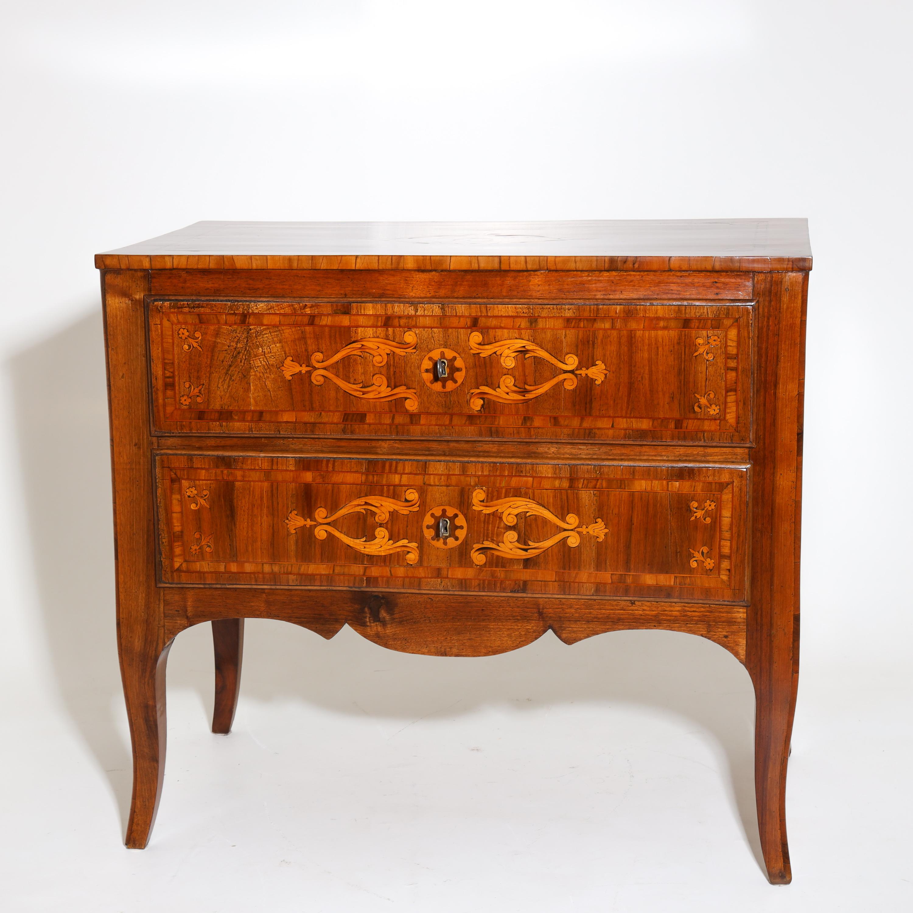 Chest of drawers standing on curved legs with two drawers and a curved apron. The chest of drawers is decorated on all sides with tendril-shaped inlays. Walnut, solid and veneered. The chest of drawers has been expertly refinished and hand-polished.