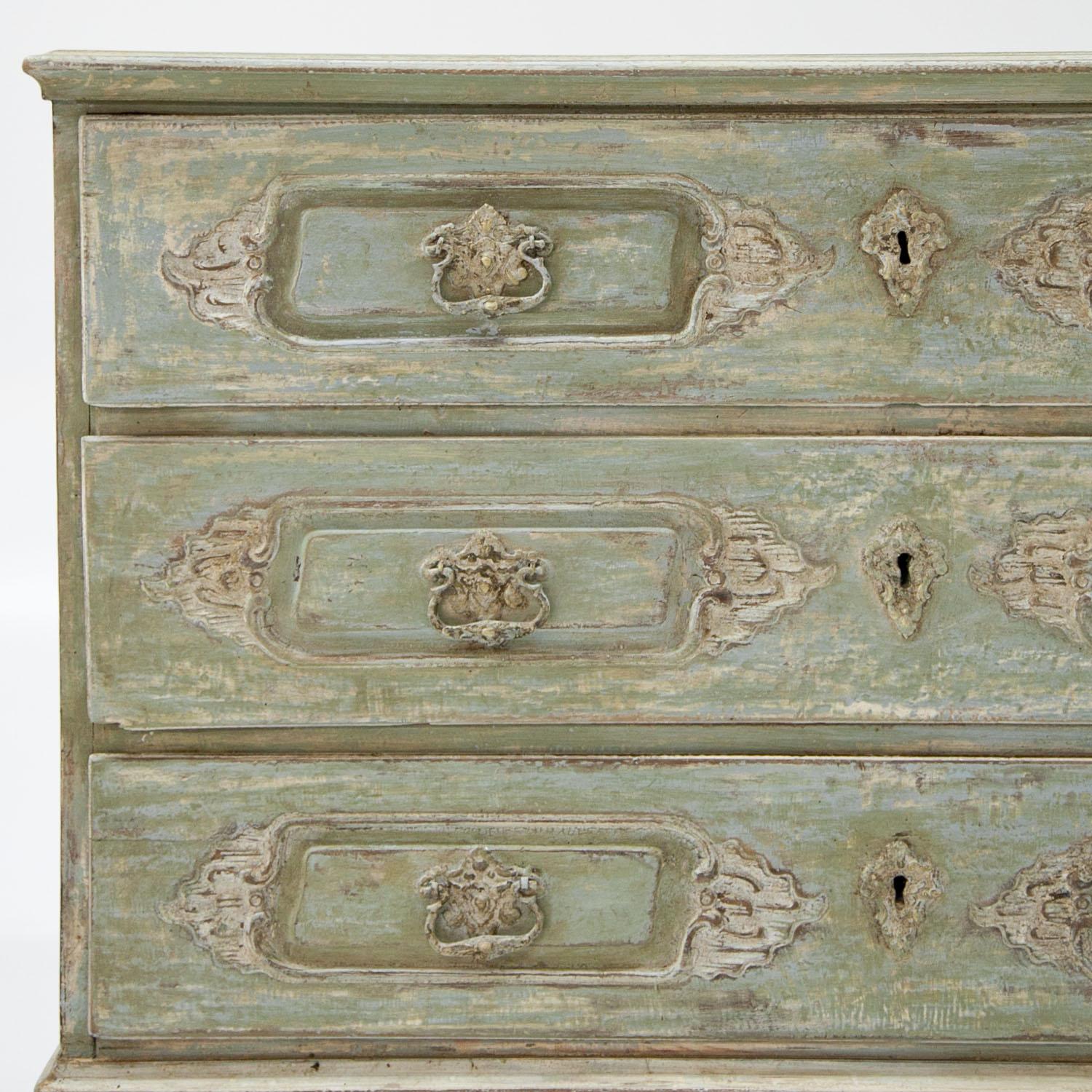 Three-drawered Baroque chest of drawers on tapered feet with rocaille cartouches at the front. The crème-white paint is new and has a distressed look to it.