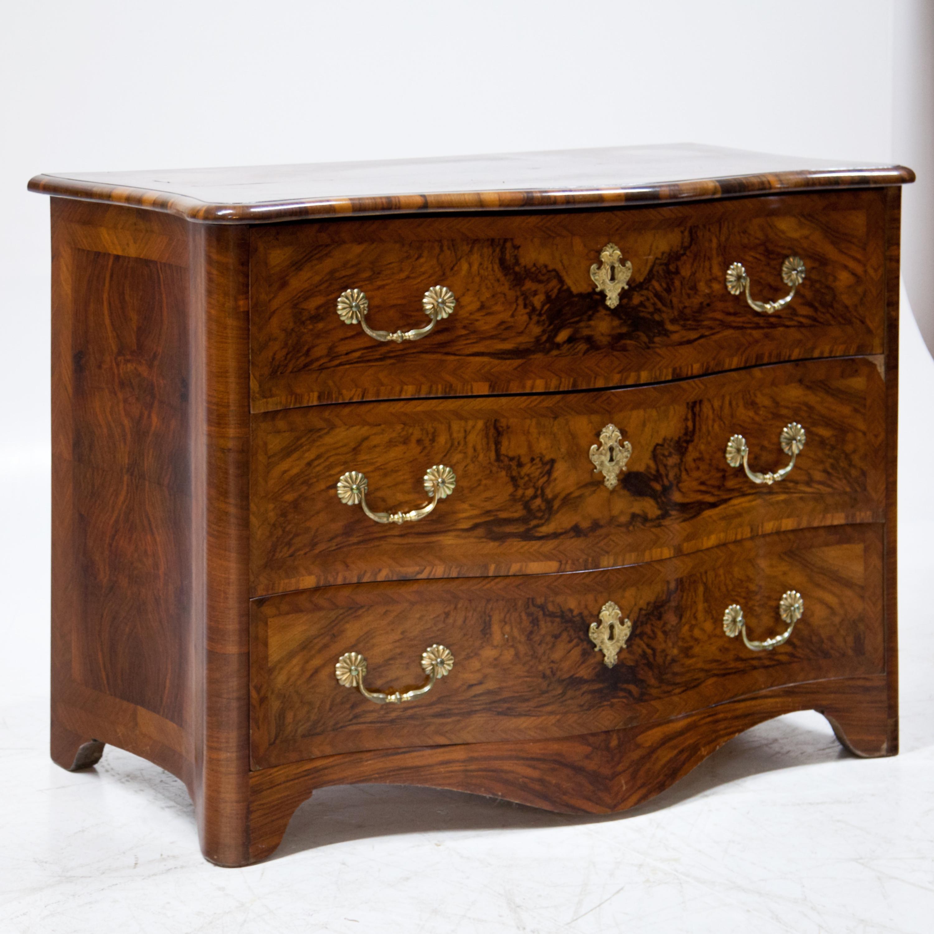 Three-door baroque chest of drawers on curved frame feet with bulbous front and concave sides. Very beautiful walnut veneer. Expertly restored condition.