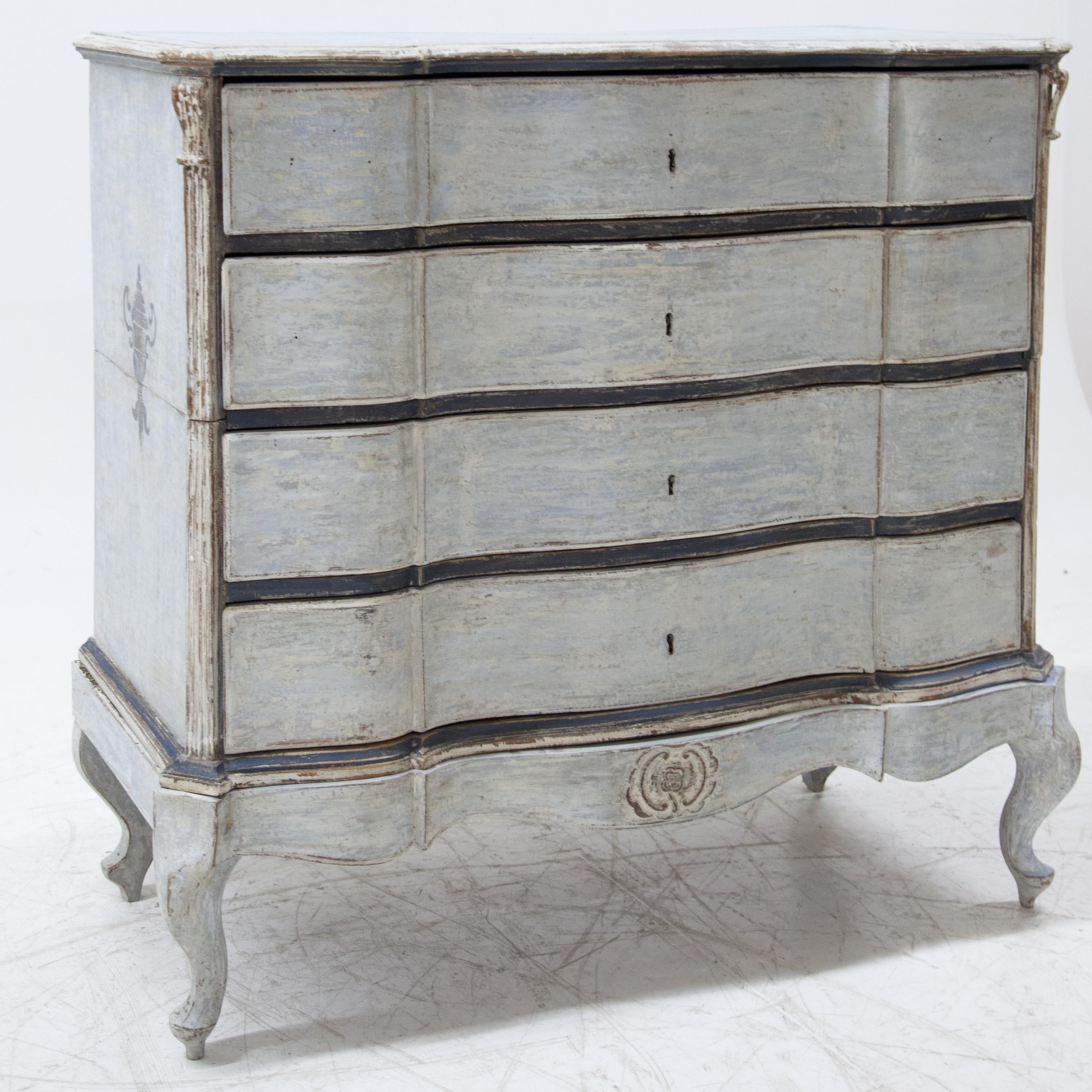 Baroque chest of drawers with four drawers and curved front standing on S-shaped curved legs and frame. The bevelled corners are fluted and end in a carved volute. The blue paint is new and has been decoratively rubbed through.