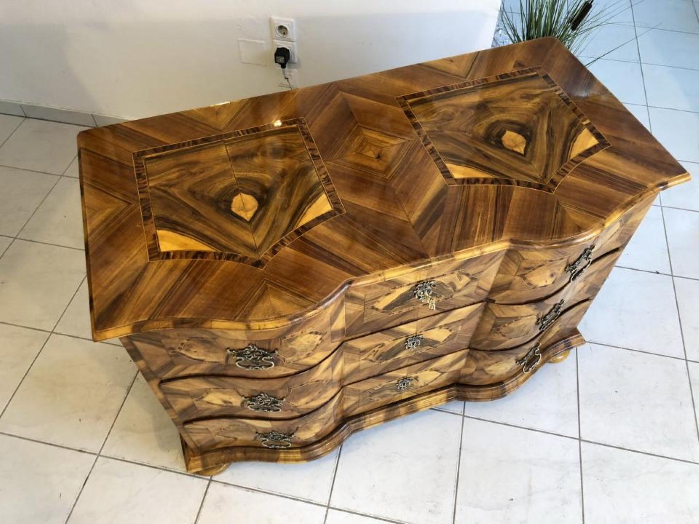 Magnificent Baroque chest of drawers with stunning marquetry work and brass handles on the front.
This is a very beautiful inlay work modern Baroque commode with three curved drawers.
Features symmetrical veneer patterns and a high gloss polished