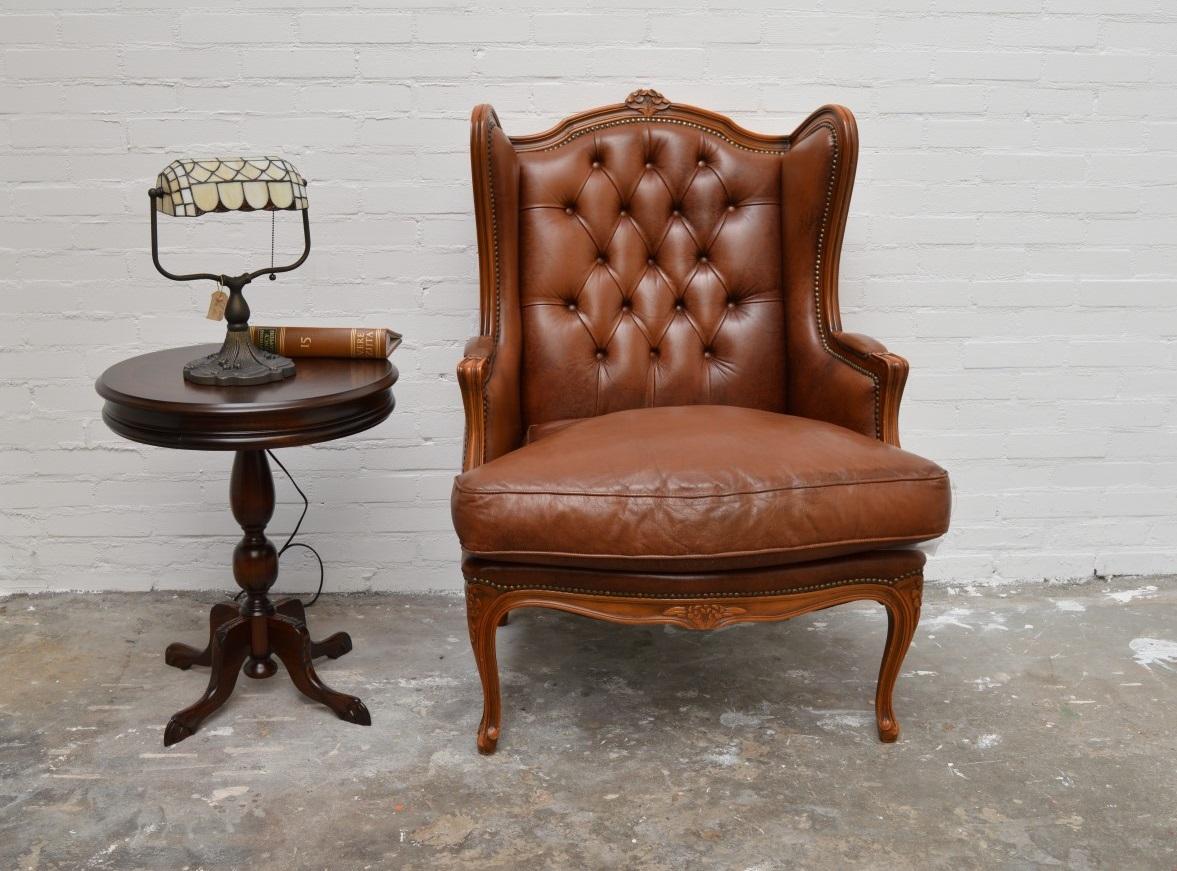 Very nice Baroque Chesterfield wing chair which is kept in the authentic and original state. Leather is hand dyed and in excellent condition and fine wooden frame with elegant wooden details. Note that this chair is not 