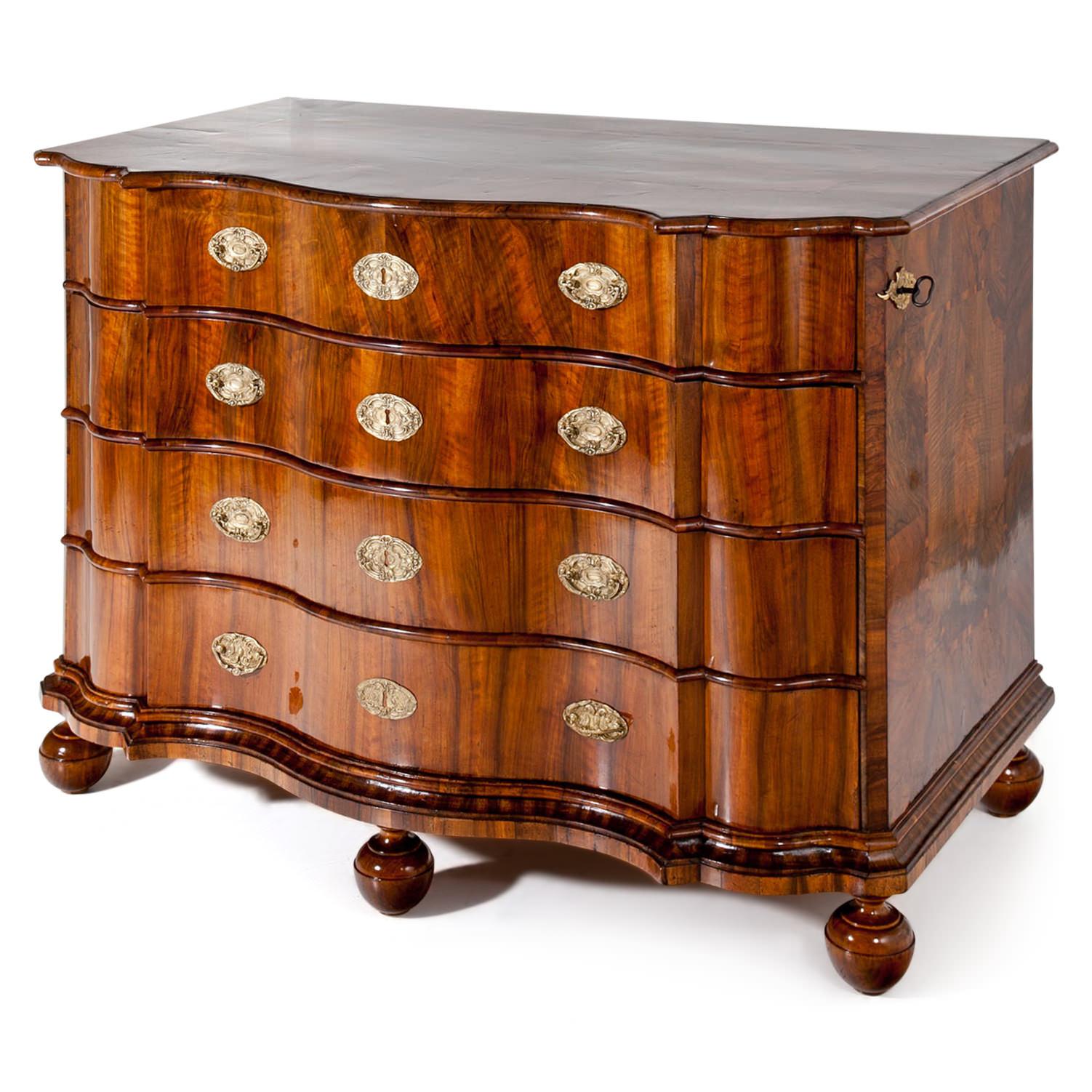 Baroque chest of drawers with a serpentine front, standing on ball feet. The four drawers can be locked on the right side, the key exists. The commode is in a hand-polished and refurbished condition.