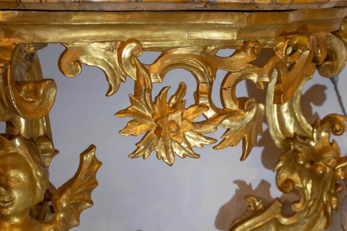 Baroque console 
Gilded wooden console in Baroque style.
Top in yellow veined Sienna marble with a scrolled edge in an earlier Louis XV style. Traces of restoration are visible but blend in with the decoration.
19th century.
Measures: H 86 cm, W