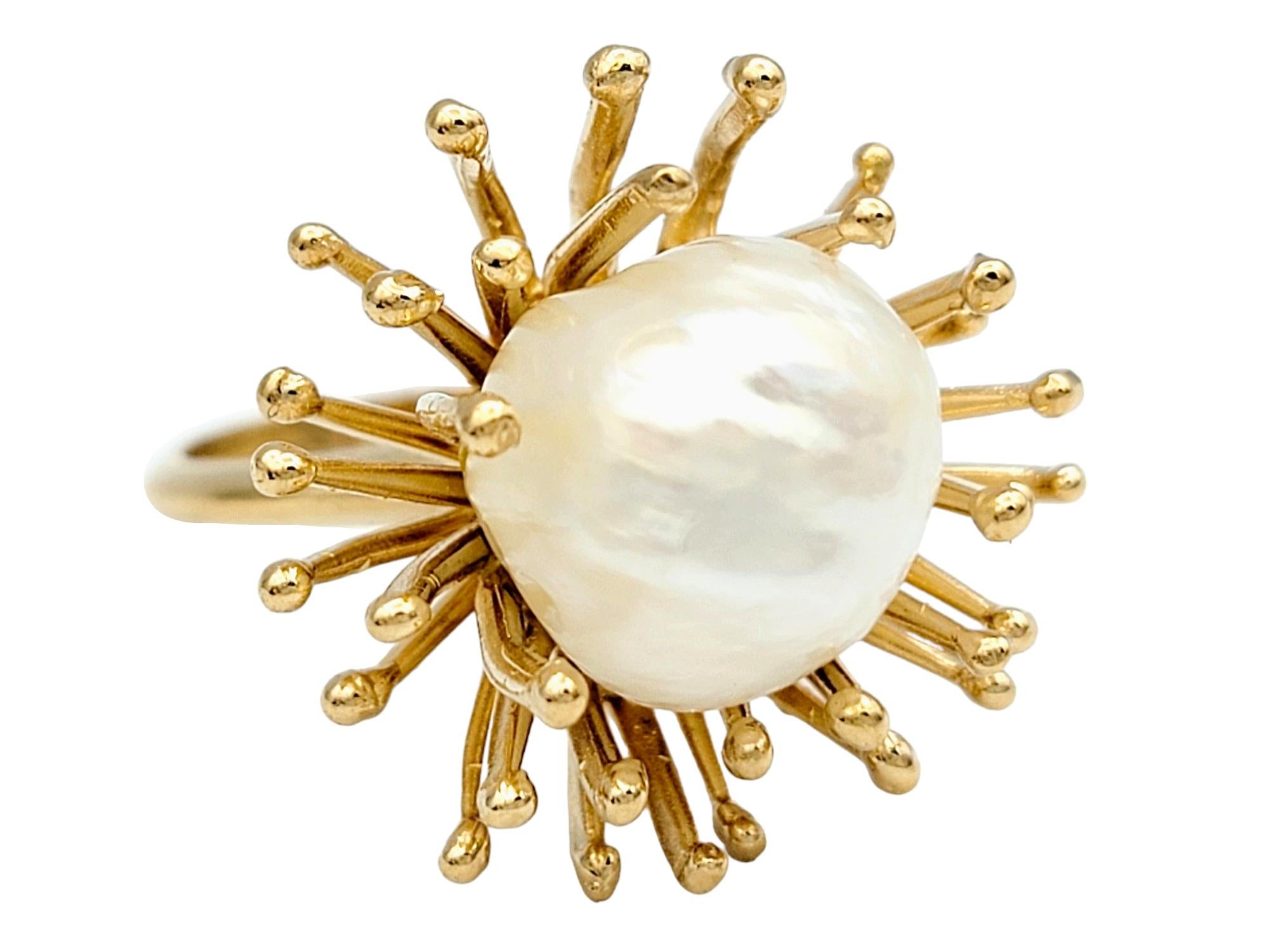 Ring Size: 6

This exquisite ring showcases the natural beauty of a baroque white cultured pearl, elegantly complemented by a unique spiky spray motif. The organic curves of the spray design delicately wrap around the pearl, creating a sense of