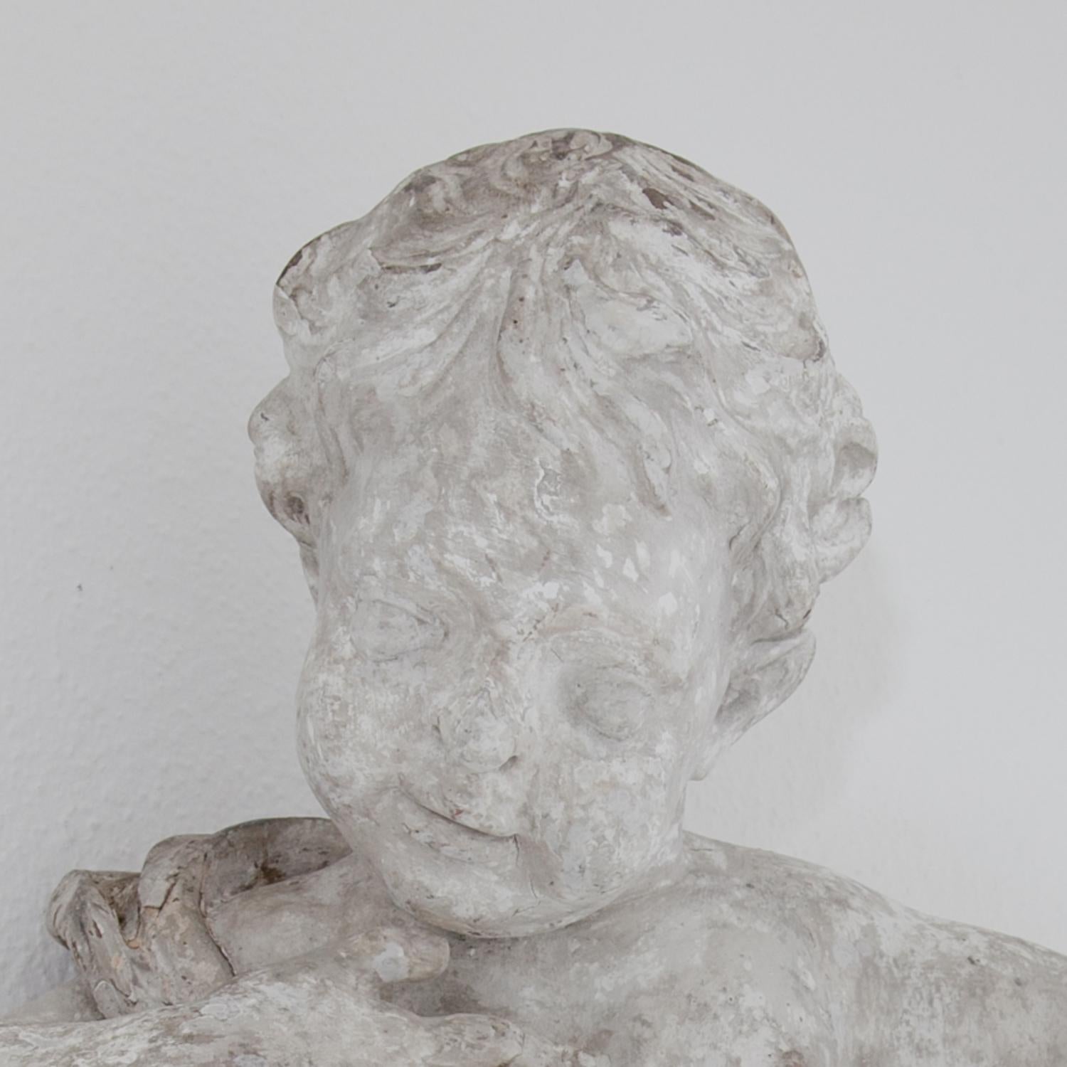 White painted baroque putto with look to the left. His right hand goes to his heart; his left arm opens up in a welcoming gesture. Cleaned and minimally restored.