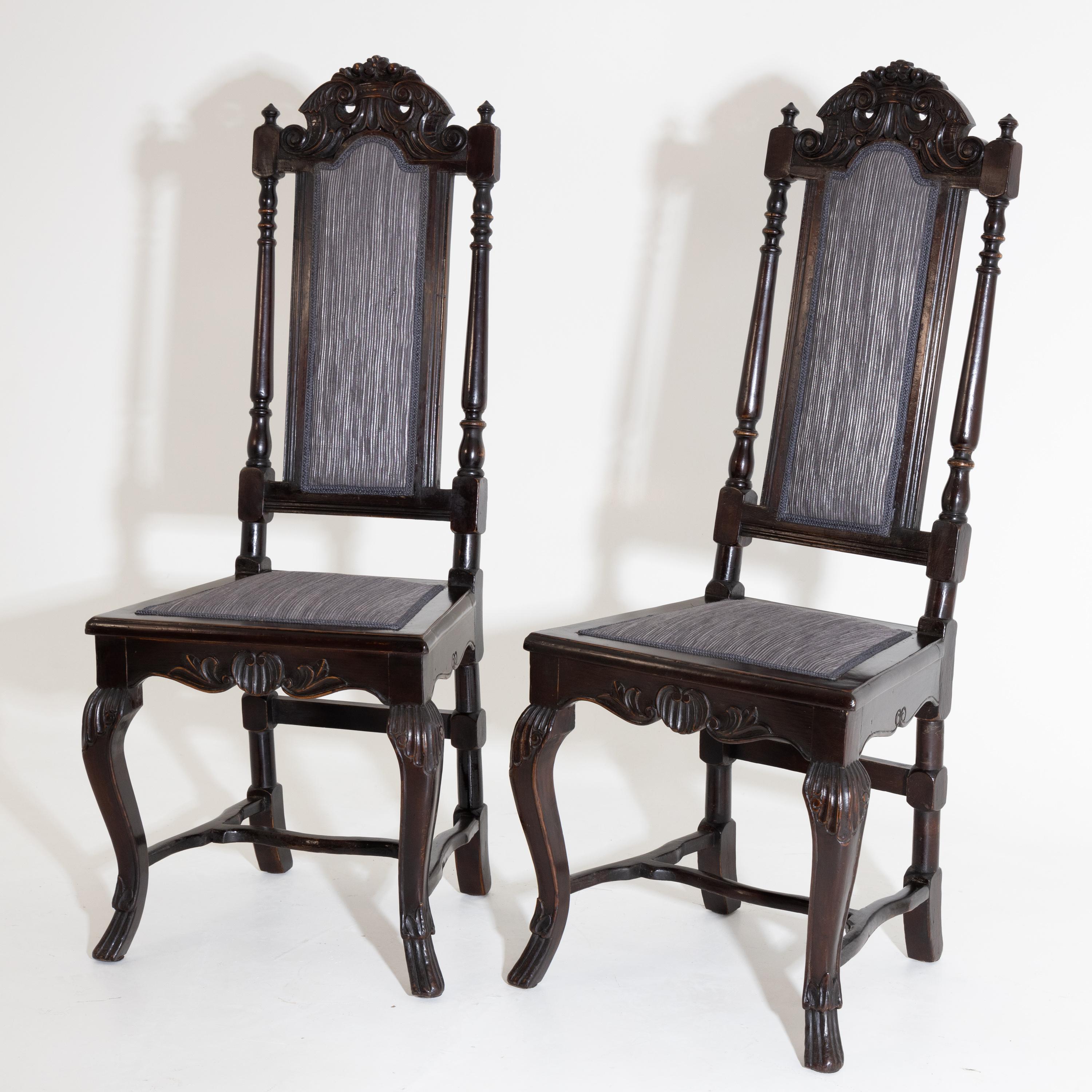 Pair of baroque chairs with carved backs with pinnacles, balustraded columns and shell decoration and H-shaped bracing between the curved legs.
  