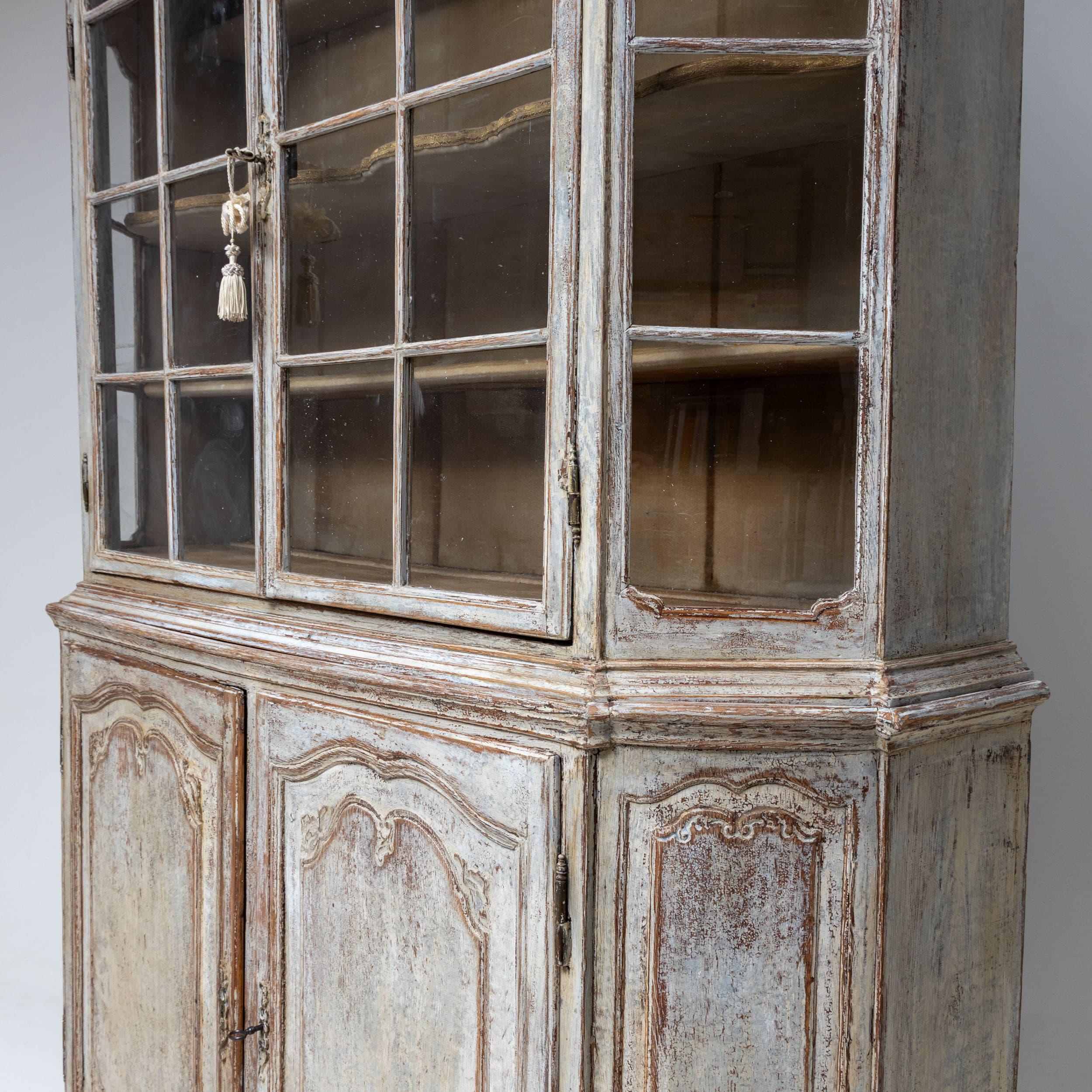 Magnificent Baroque display cabinet with chamfered corners and a glazed upper section, topped with a gracefully curved pediment adorned with carved volute decorations. The glass-panelled doors feature elegant mullions. The interior offers three