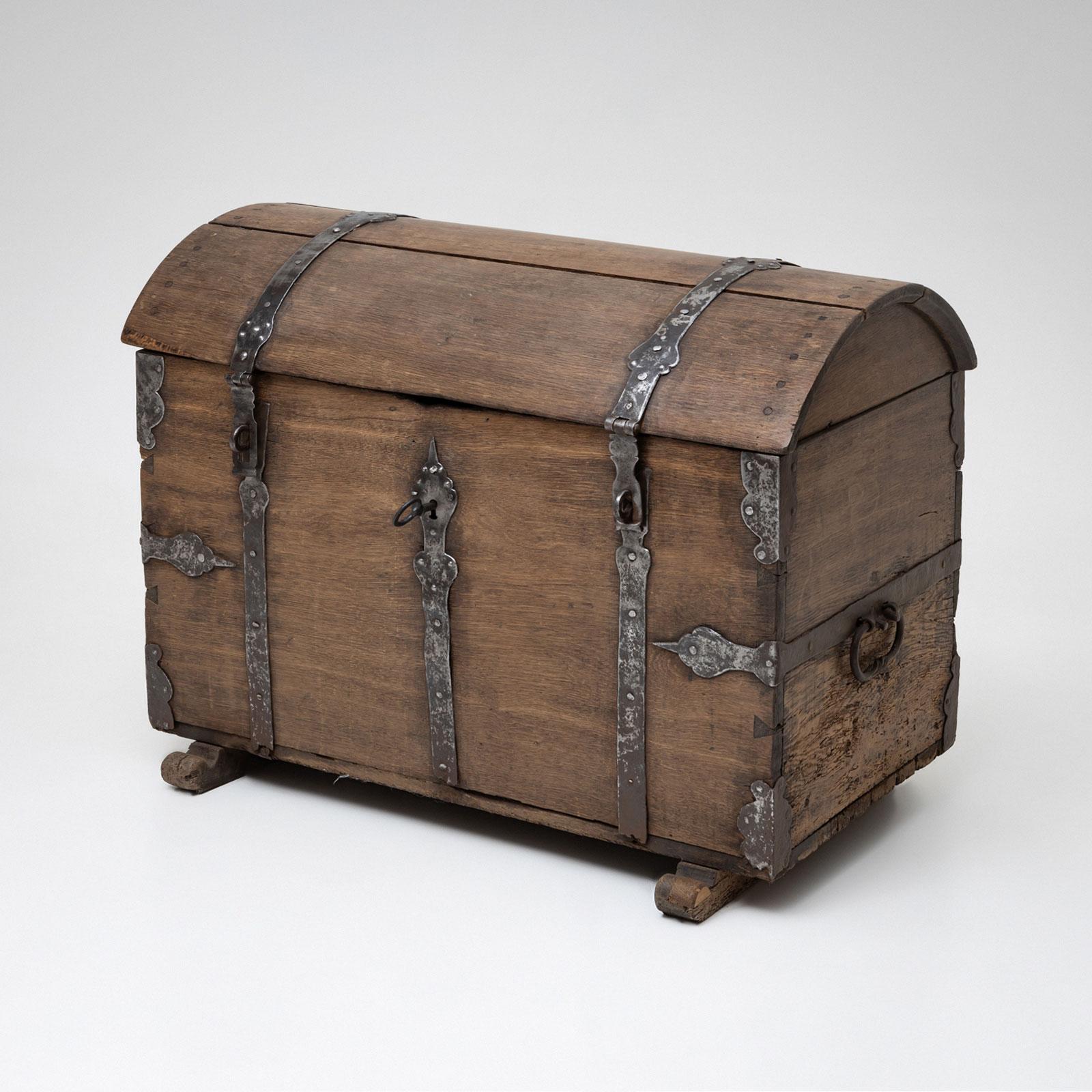 An Baroque domed chest crafted from oak, dating to the first half of the 18th century. The chest features intricate iron fittings and side handles, combining both decorative and functional elements.

The interior has been lined with a cheerful