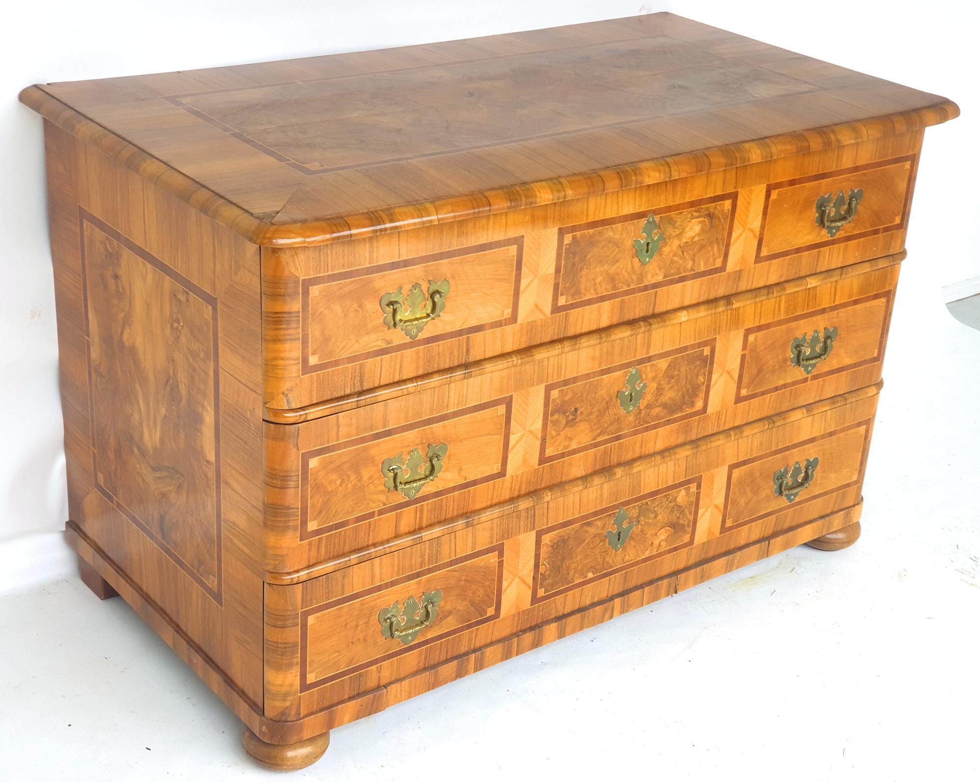 Elegant baroque dresser in walnut and other precious woods. 1770s

Pressed ball feet, above a body with rounded corners and three drawers. The drawers are divided into three sections by ribbon and thread inlays. Original fittings and locks. Cover