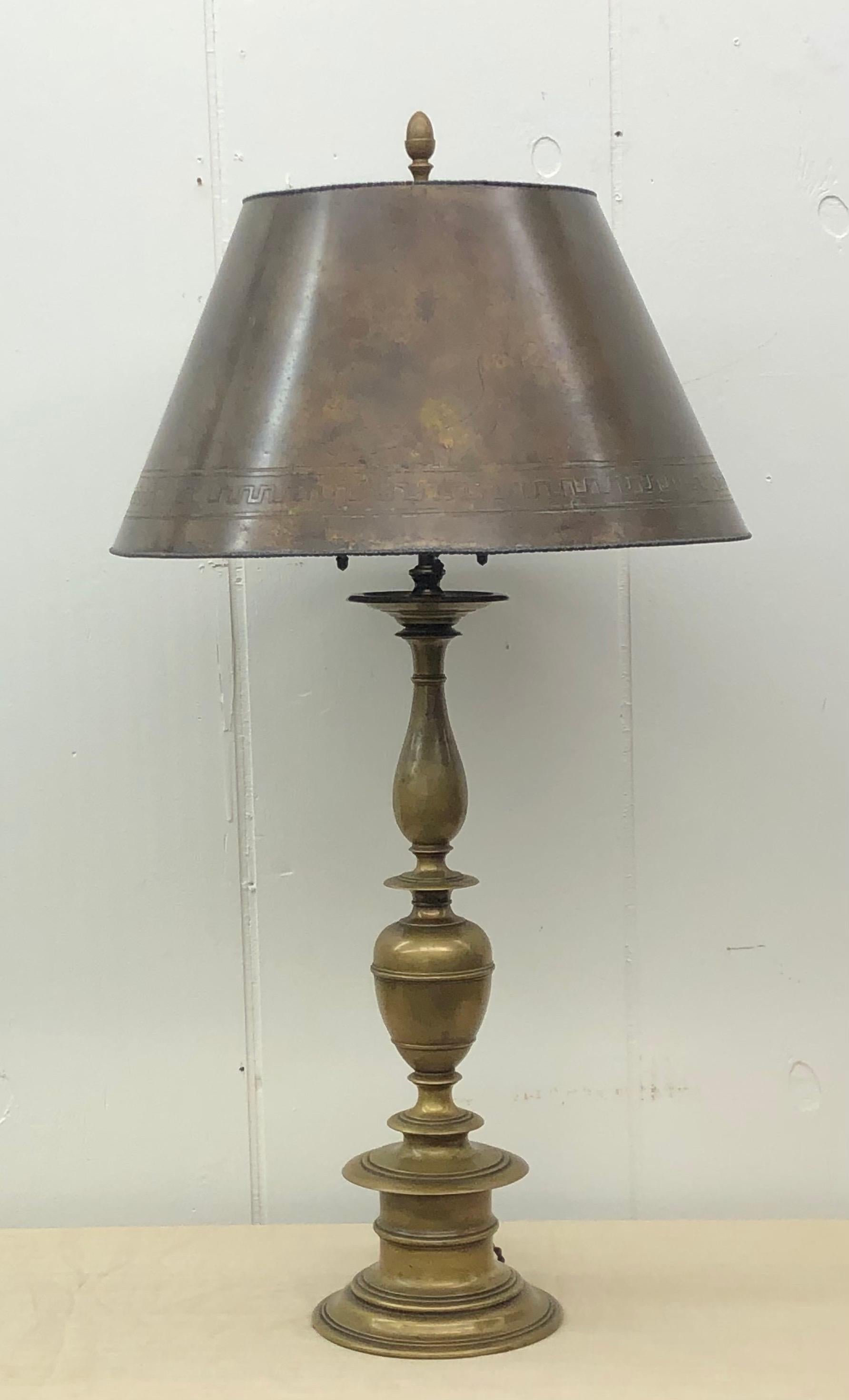 Elegant Caldwell lamp in the Baroque style with baluster standard toped with original three light cluster and final. The brass shade has a pressed Greek key design with reel and rod edging on the top and bottom of the shade. The patinated shade is