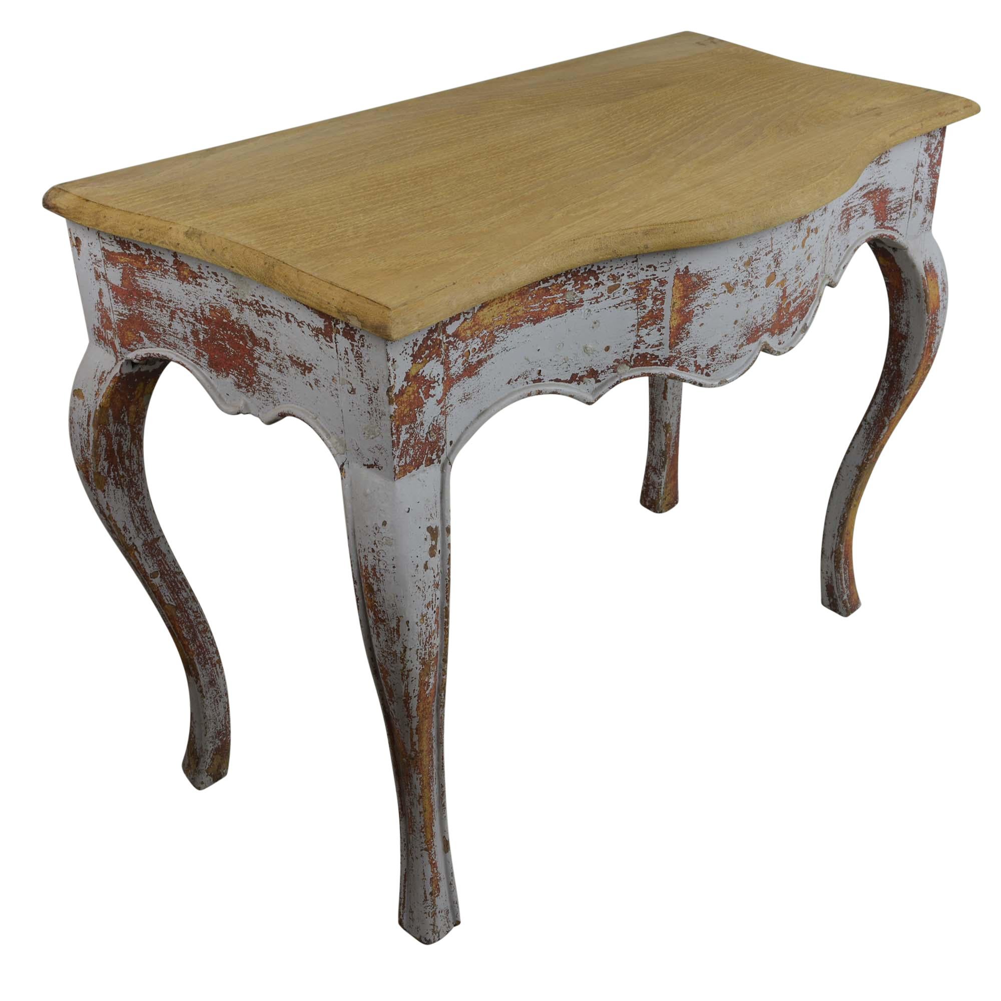 The base of the table is early 18th century and features a scalloped front apron and slender curved cabriole legs, the antique console table is painted gray with an undercoat of red paint showing through in places. In some areas the paint is