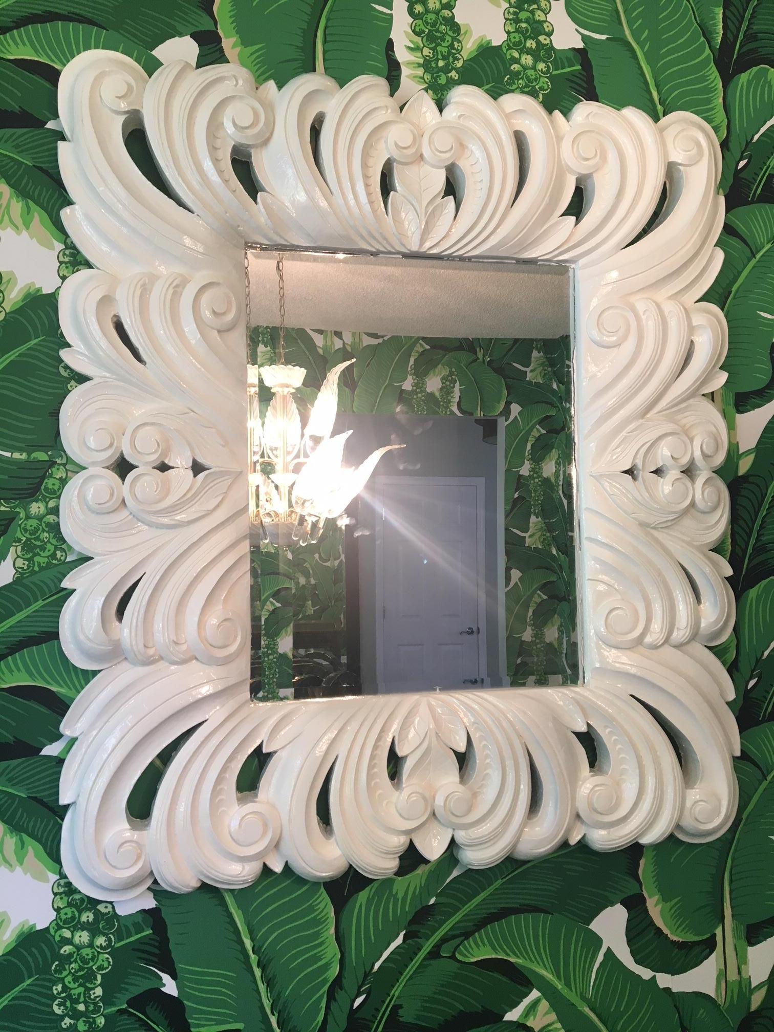 Large wall mirror in the style of designer Dorothy Draper features a beveled edge and glossy white finish. Ornate frame makes a bold statement in an entryway or living space. Molded composite frame. Very good vintage condition with no flaws to speak