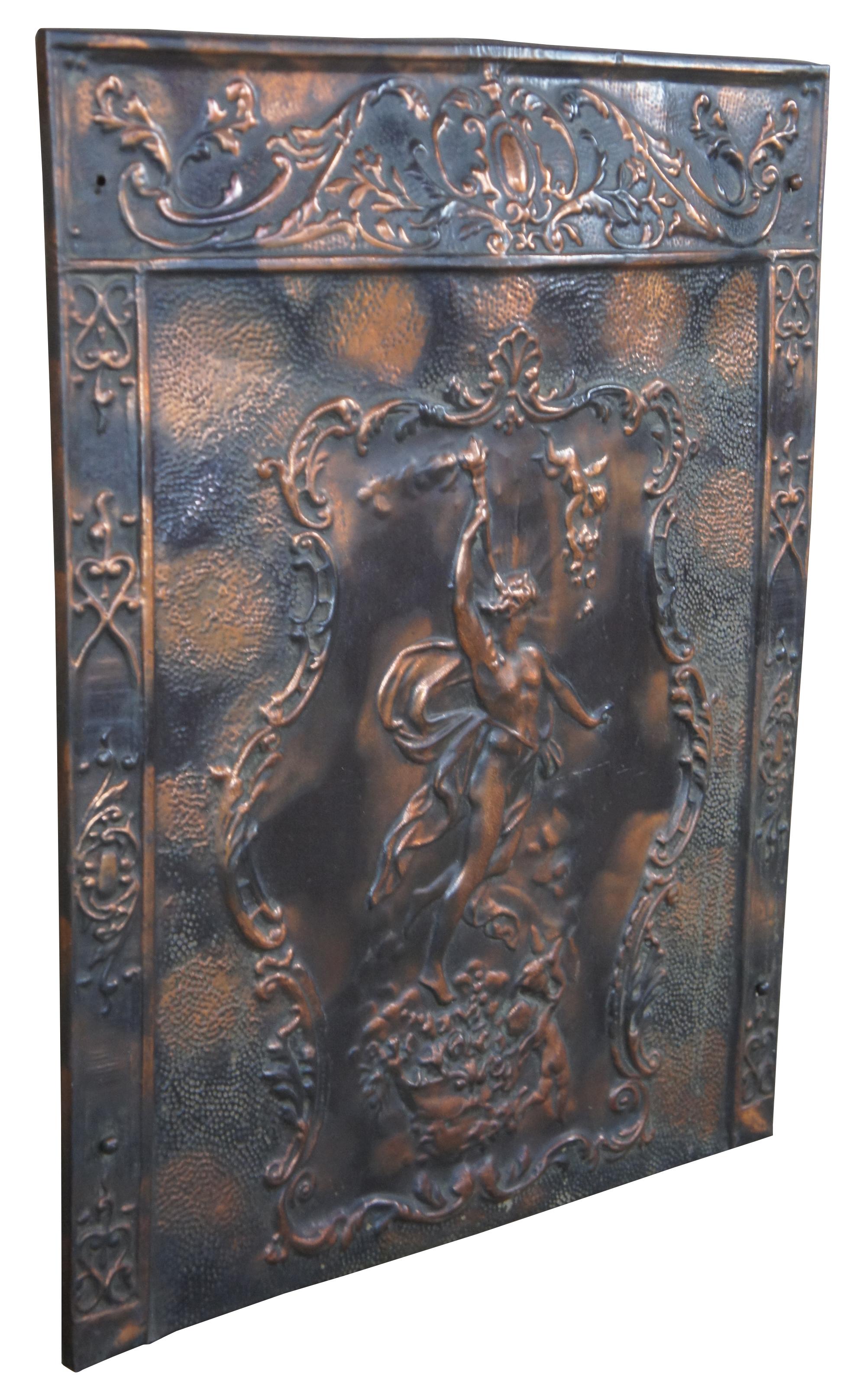 Vintage fireplace summer cover (sometimes called firebacks) or wall plaque. Made of metal with pressed image of Comis carrying a torchère with two Cherubs in tow and floral details. Comis is the god of festivity, revels and nocturnal dalliances.