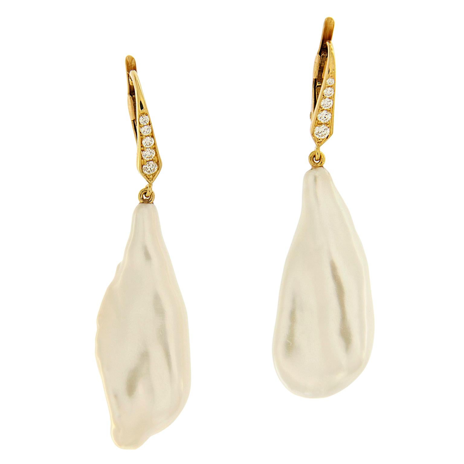 These earrings are made in 18kt yellow gold, they feature white baroque fresh water pearl drops with round brilliant diamonds set on the front of the lever backs. 