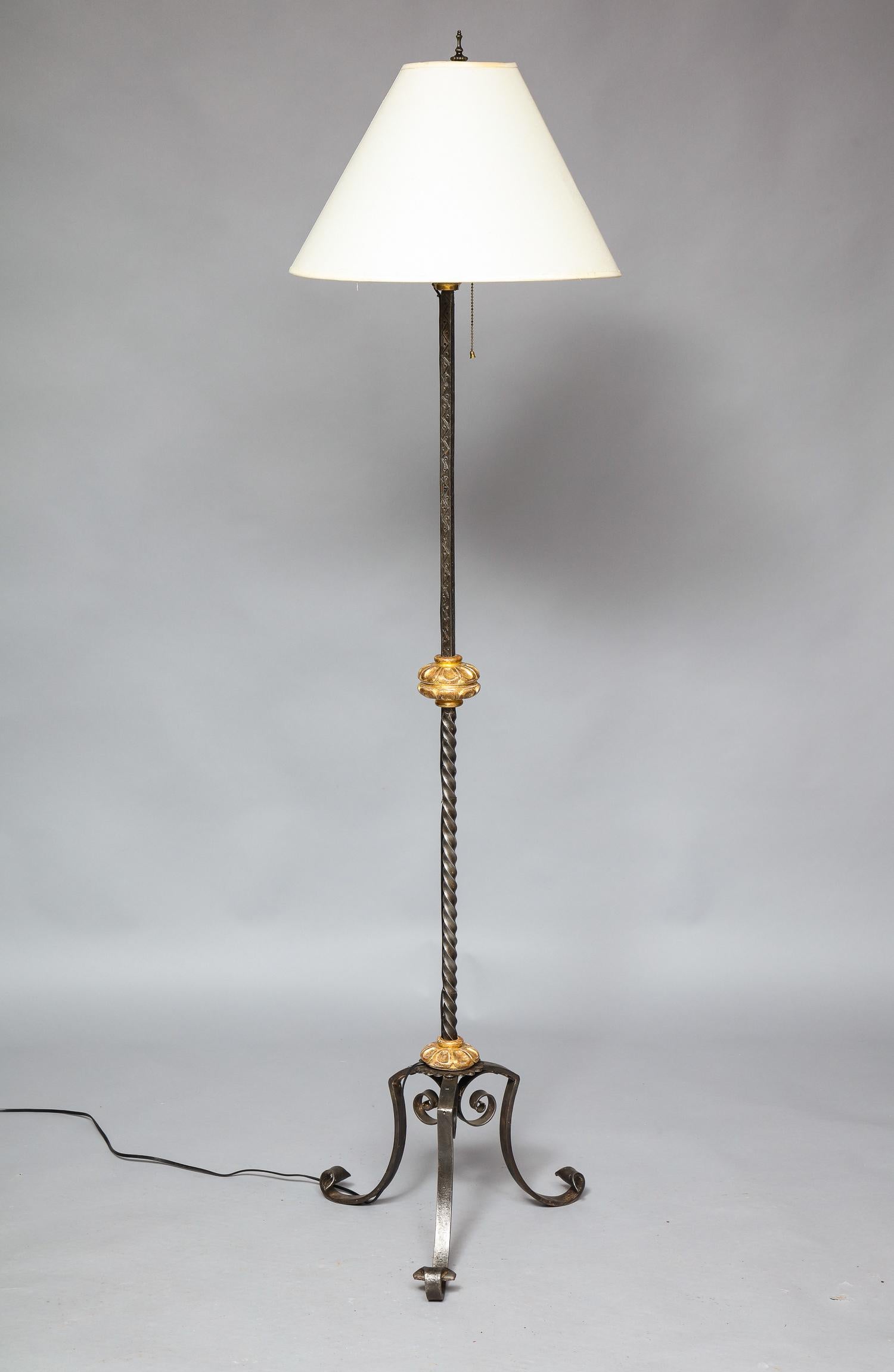 Beau lampadaire en fer forgé de style baroque du début du 20e siècle, avec cols sculptés et dorés à l'eau, le fût en torsade d'orge avec décor gravé, reposant sur des pieds en fer forgé à volutes, l'ensemble présentant une agréable surface patinée
