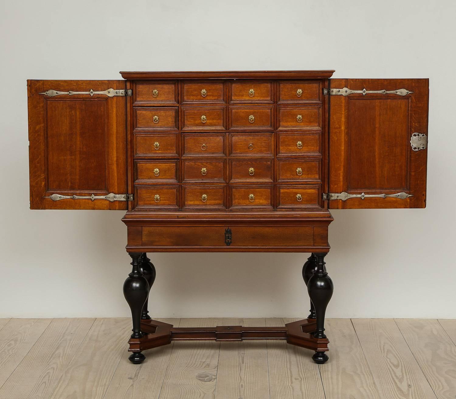 A fine Baroque Scandinavian cabinet on stand, circa 1740-1770, origin: Stockholm, Sweden, interior fitted with smaller spice drawers with bottom drawer, mahogany veneer with ebonized feet, pewter and brass hardware.
